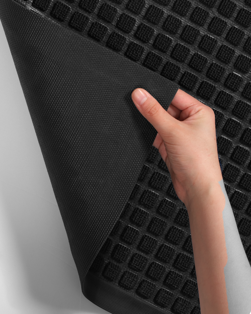 Absorbent entryway rug with natural rubber border prevents curling and water leaks.
