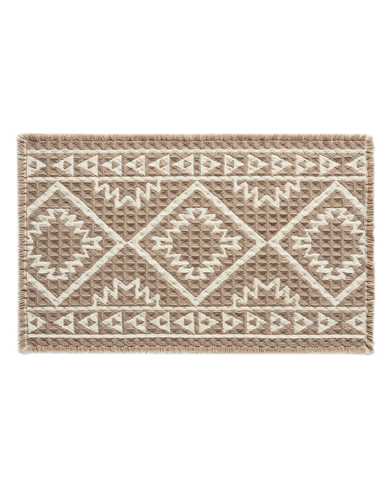 Waffle bath mat with decorative tassels, machine washable, soft, and absorbent.