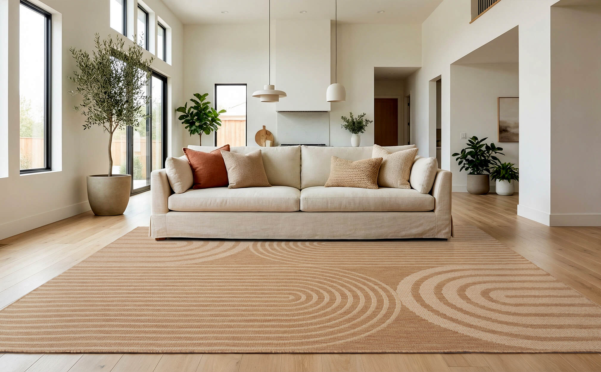 A brown abstract indoor outdoor rug with a modern arched line pattern adds warm texture to a bright living room with a cream sofa, wood floors, neutral pillows, and airy contemporary decor.