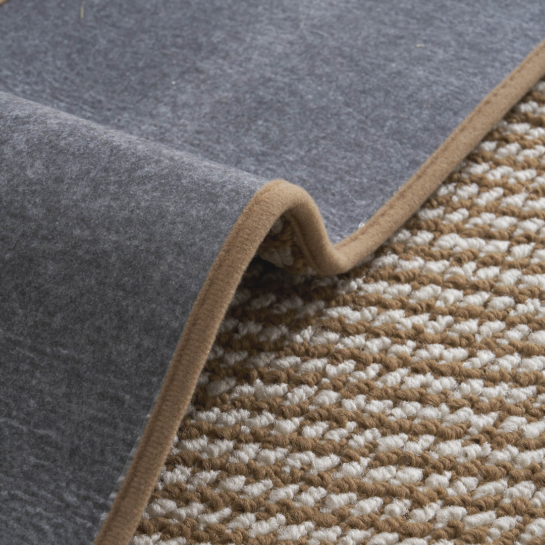 A close-up of brown gradient striped woven stair treads highlights their raised diagonal woven texture, soft cushioned surface, flexible gray non-slip backing, and neatly bound edges, offering comfortable footing, reliable grip, and practical protection for indoor wooden staircases.