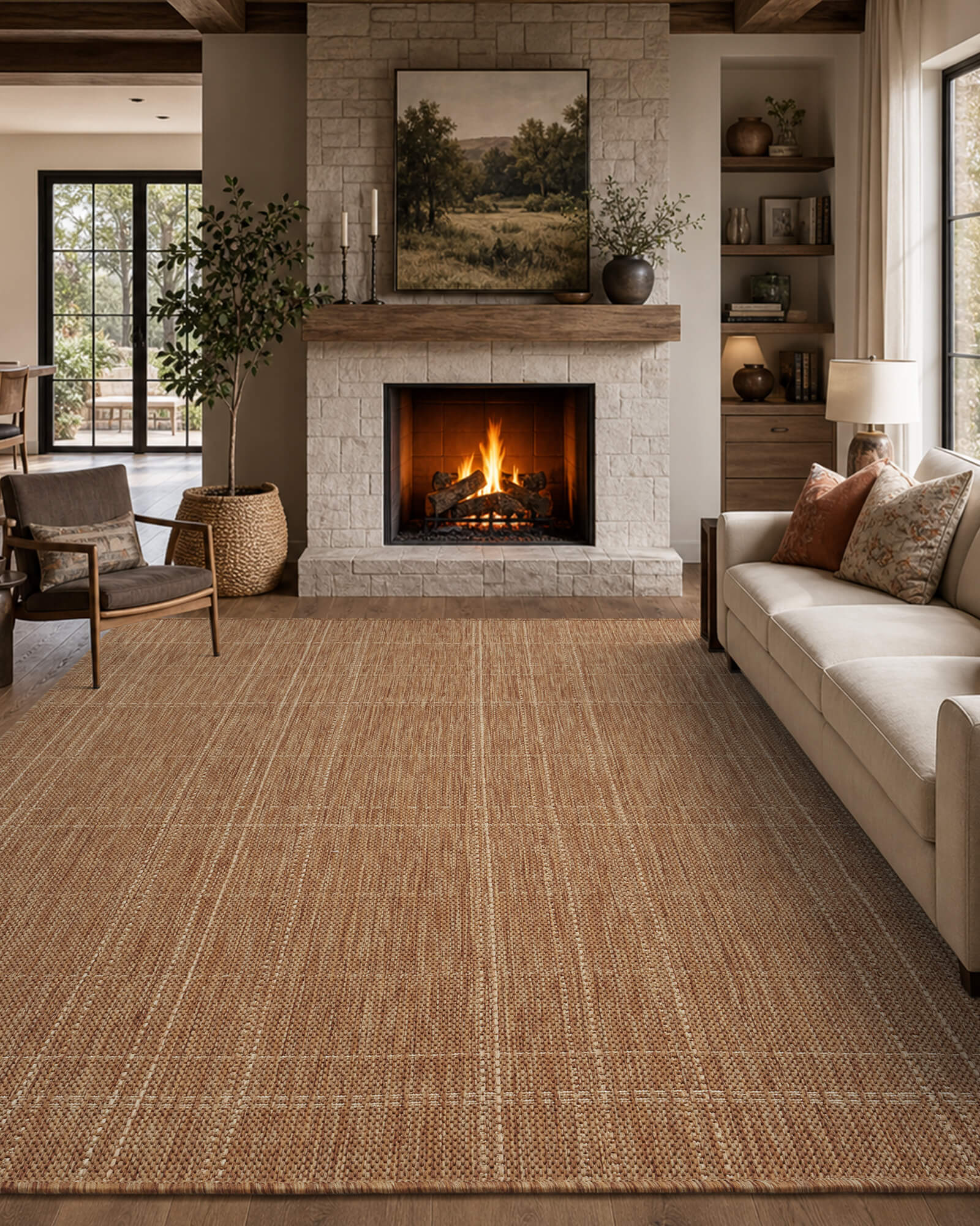A brown plain weave indoor outdoor rug with a subtle grid border adds warm woven texture to a cozy fireplace room with a cream sofa, built-in shelves, wood beams, and relaxed farmhouse decor.