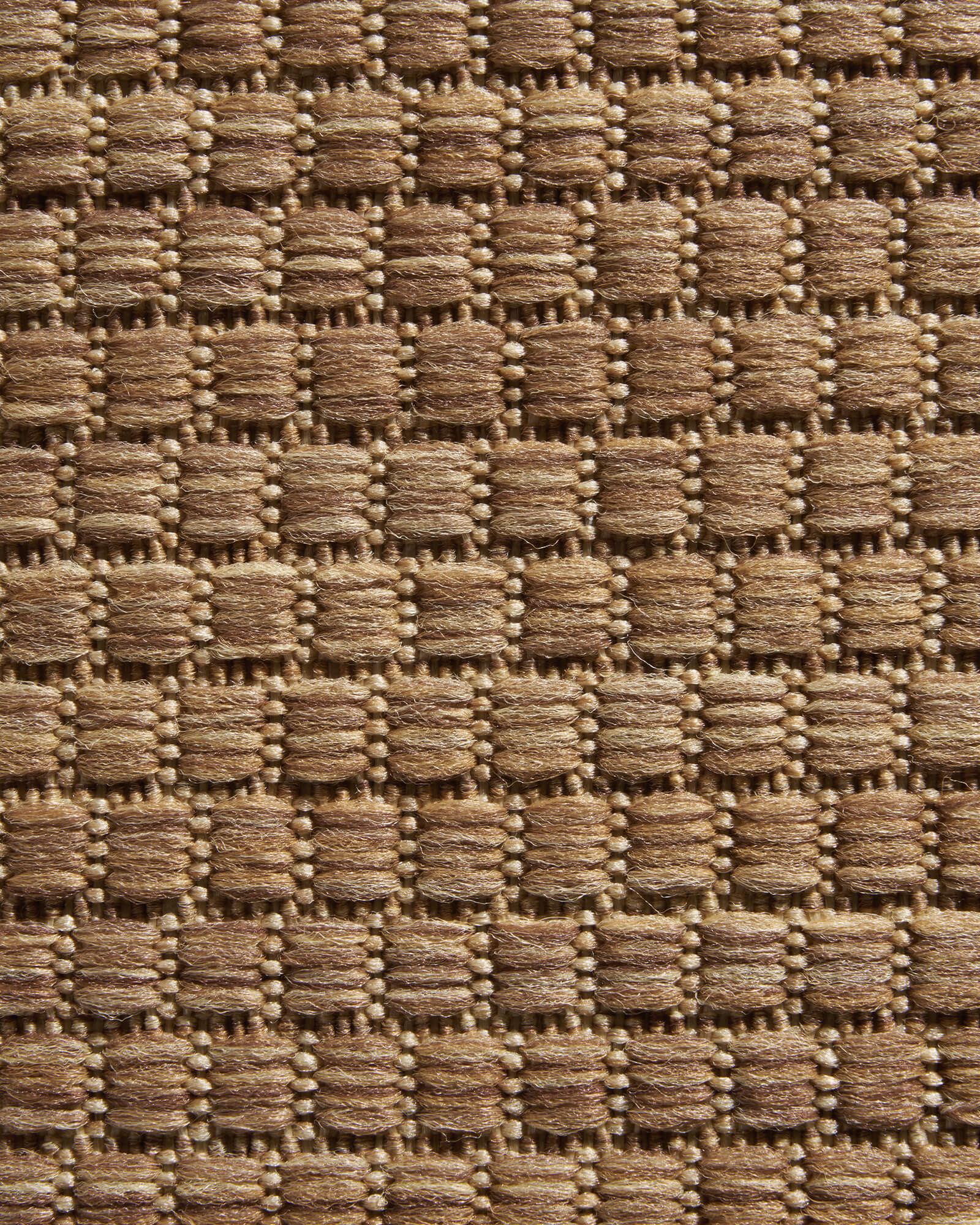 A close-up view of a brown plain weave outdoor rug highlights its raised basketweave texture, durable woven surface, and natural outdoor style for patios, decks, porches, and entryway spaces.