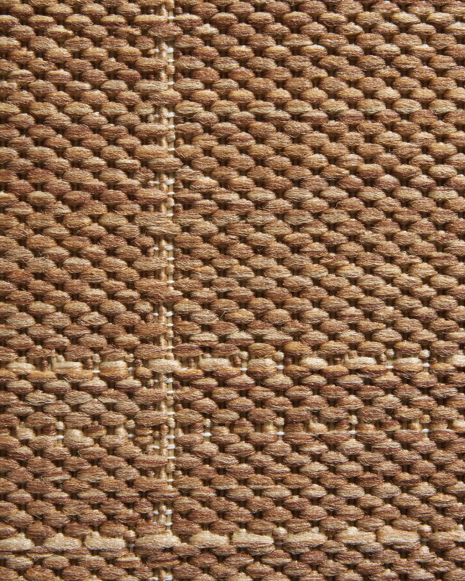 A macro close-up of a brown plain weave outdoor rug highlights its subtle grid texture, raised woven surface, and durable natural look for patios, decks, porches, and outdoor living spaces.