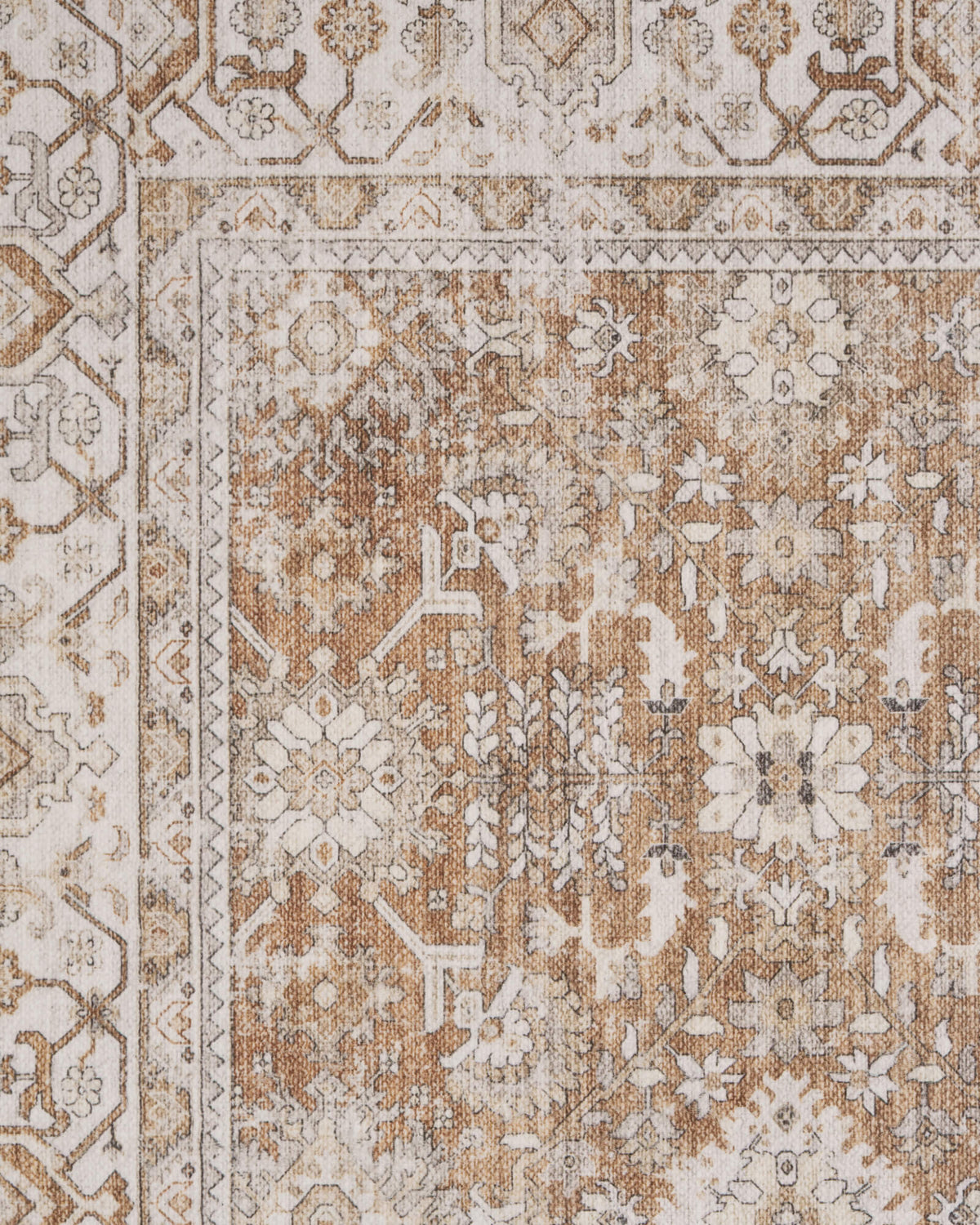 A close-up view of a brown vintage washable area rug highlights its distressed floral medallion pattern, ornate border details, and warm neutral tones for classic living room, bedroom, and farmhouse decor.