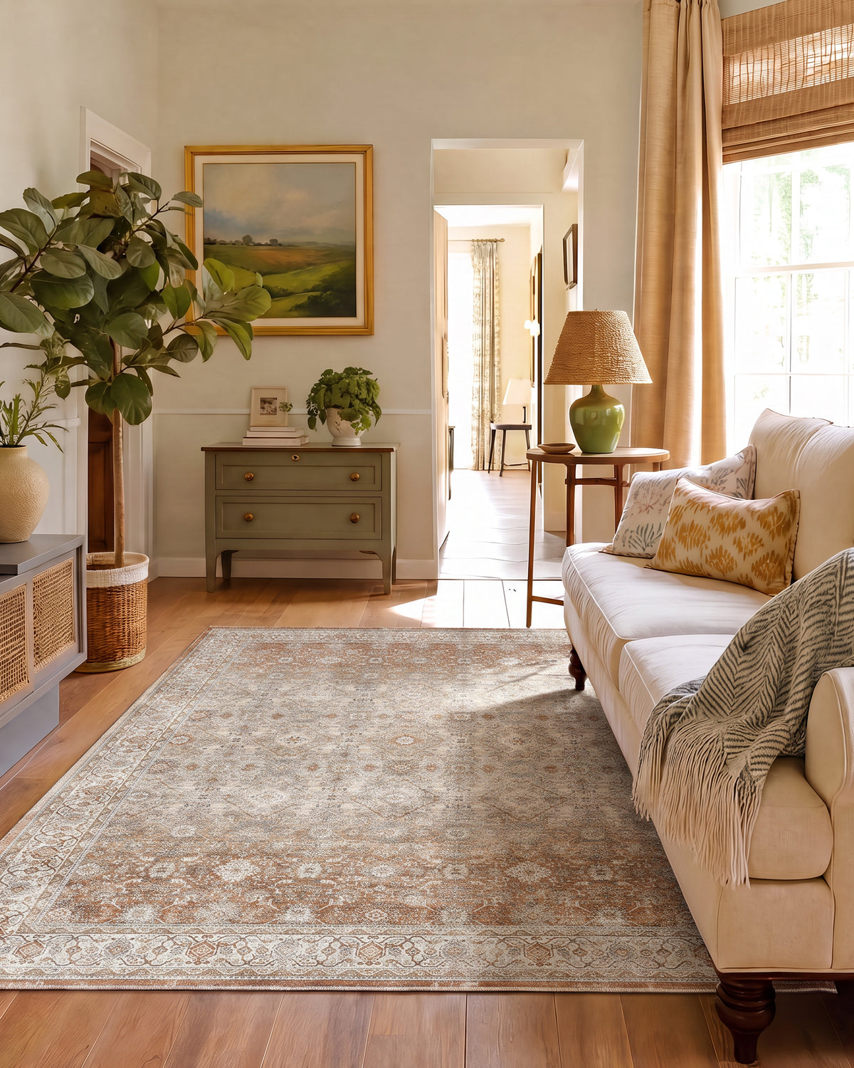 A brown vintage washable area rug with a distressed medallion pattern and ornate border adds warm traditional charm to a cozy living room with a cream sofa, wood floors, natural light, and layered home decor.