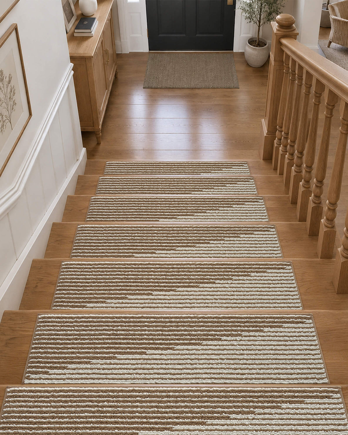 Brown and white striped non-slip stair treads neatly line a wooden staircase leading to a welcoming entryway, featuring a soft ribbed woven texture, neatly bound edges, and a warm neutral striped pattern that provides comfortable footing, helps protect hardwood steps, and adds cozy, timeless style to everyday home interiors.