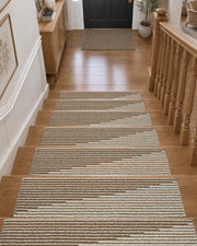 Brown and white striped non-slip stair treads neatly line a wooden staircase leading to a welcoming entryway, featuring a soft ribbed woven texture, neatly bound edges, and a warm neutral striped pattern that provides comfortable footing, helps protect hardwood steps, and adds cozy, timeless style to everyday home interiors.