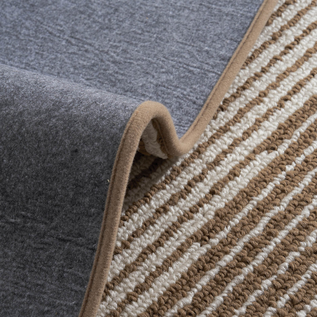 A close-up of brown and white striped woven stair treads highlights their raised ribbed texture, soft cushioned surface, flexible gray non-slip backing, and neatly bound edges, offering comfortable footing, reliable grip, and practical protection for indoor wooden staircases.
