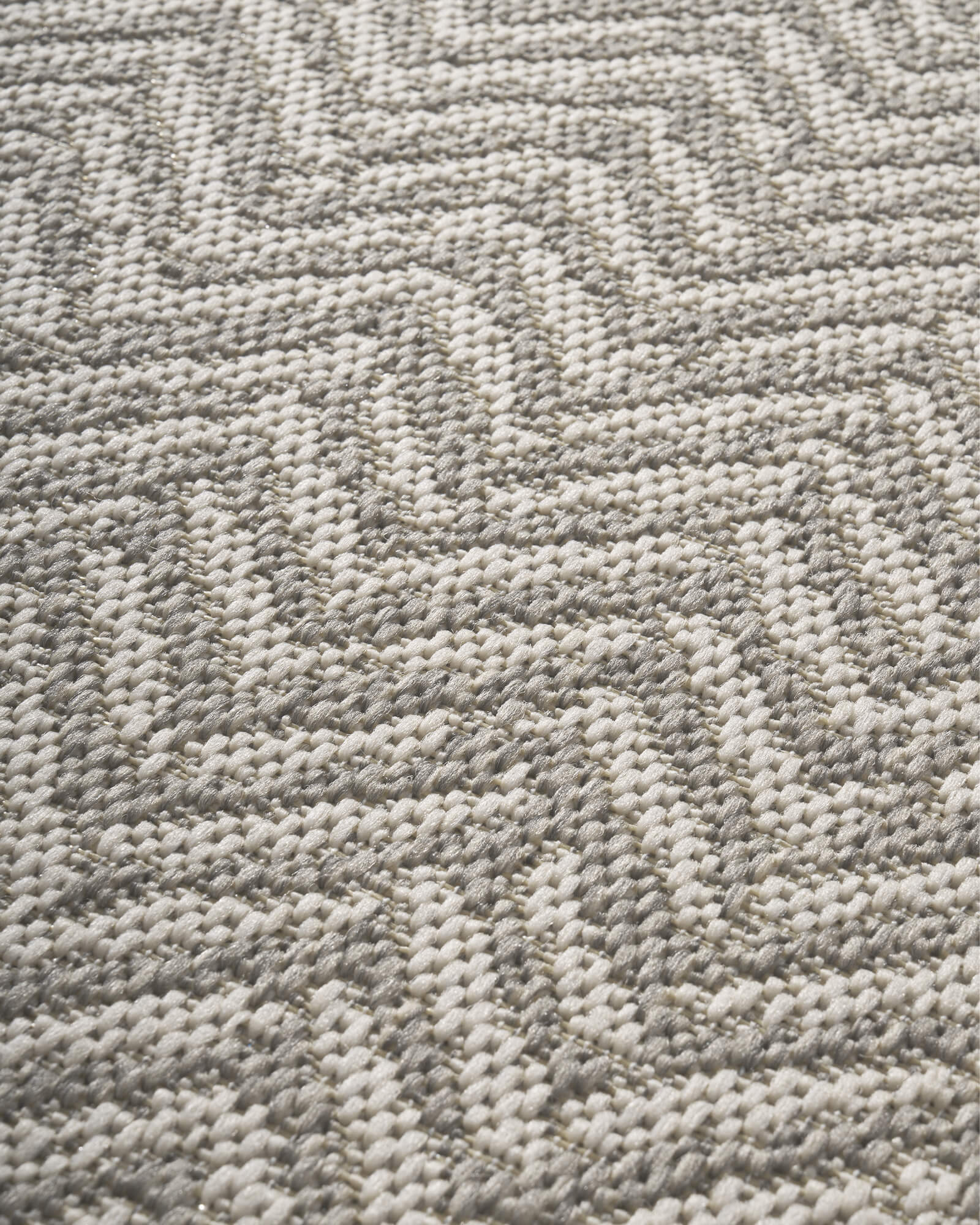 A close-up view of a gray chevron indoor outdoor rug shows its raised woven texture, durable geometric pattern, and easy-care surface for patios, porches, living rooms, and high-traffic spaces.