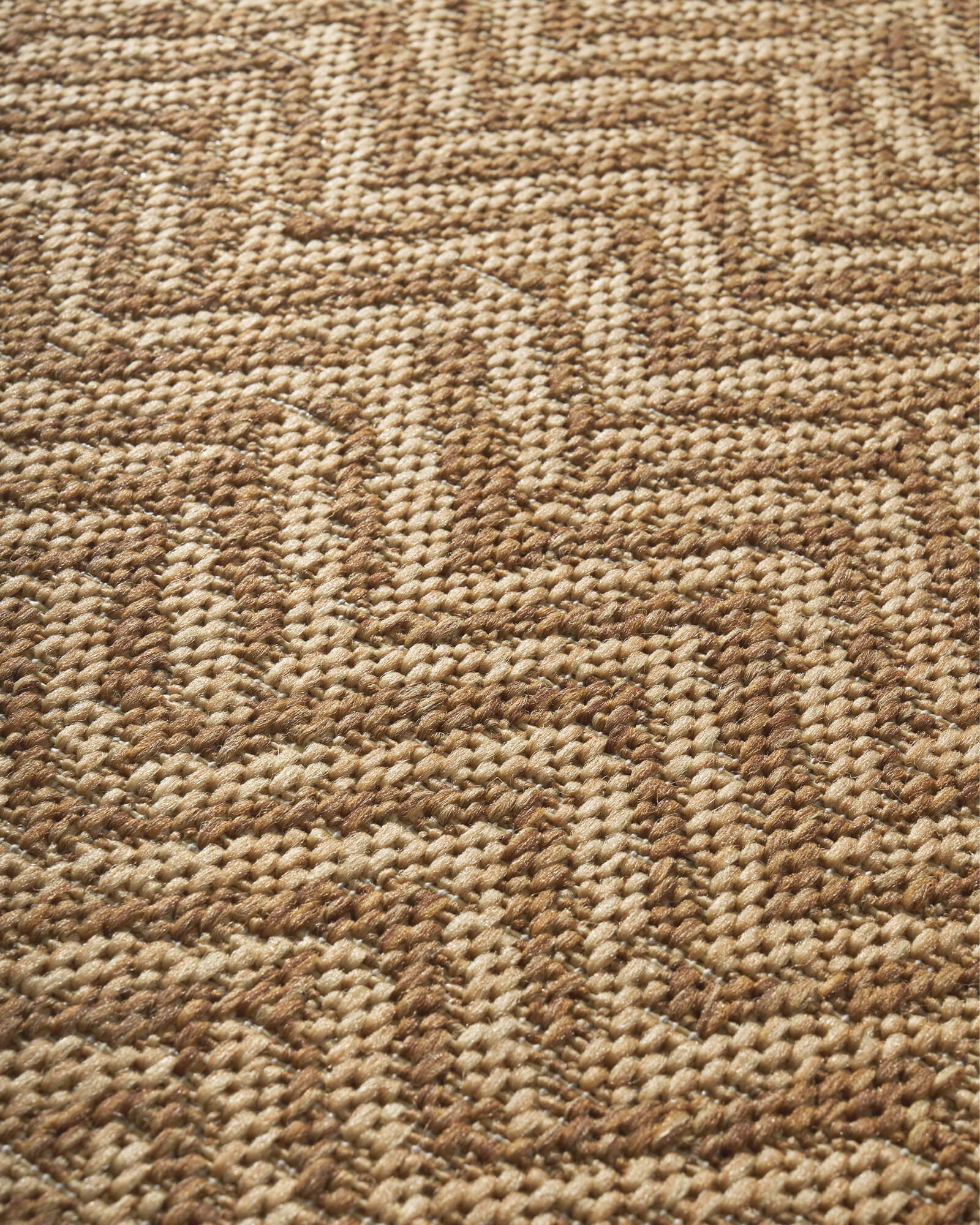 A close-up view of a natural chevron indoor outdoor rug shows its durable woven texture, raised geometric pattern, and easy-care surface for patios, porches, living rooms, and high-traffic spaces.