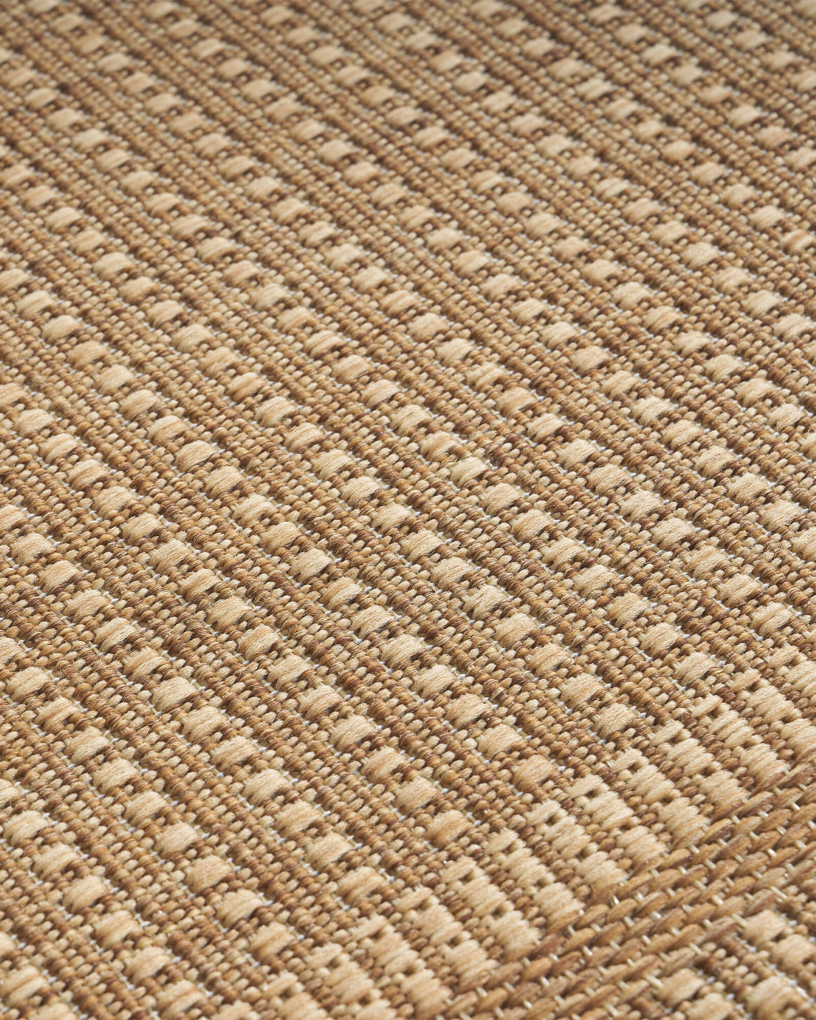 A close-up view of a natural woven indoor outdoor rug shows its durable jute-look texture, low-maintenance surface, and versatile style for patios, porches, and indoor spaces.