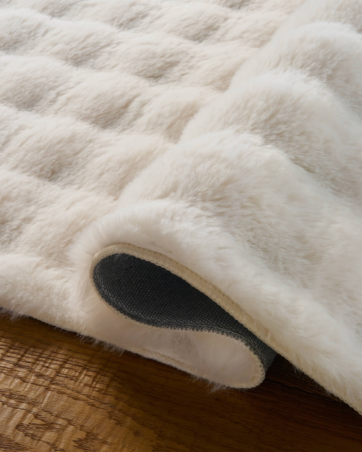 A close-up of a cream Cloud Soft shag area rug showcases its gently folded edge, exceptionally fluffy long-pile fibers, plush cloud-like softness, and textured non-slip backing, bringing luxurious barefoot comfort and inviting warmth to cozy bedrooms and living spaces.