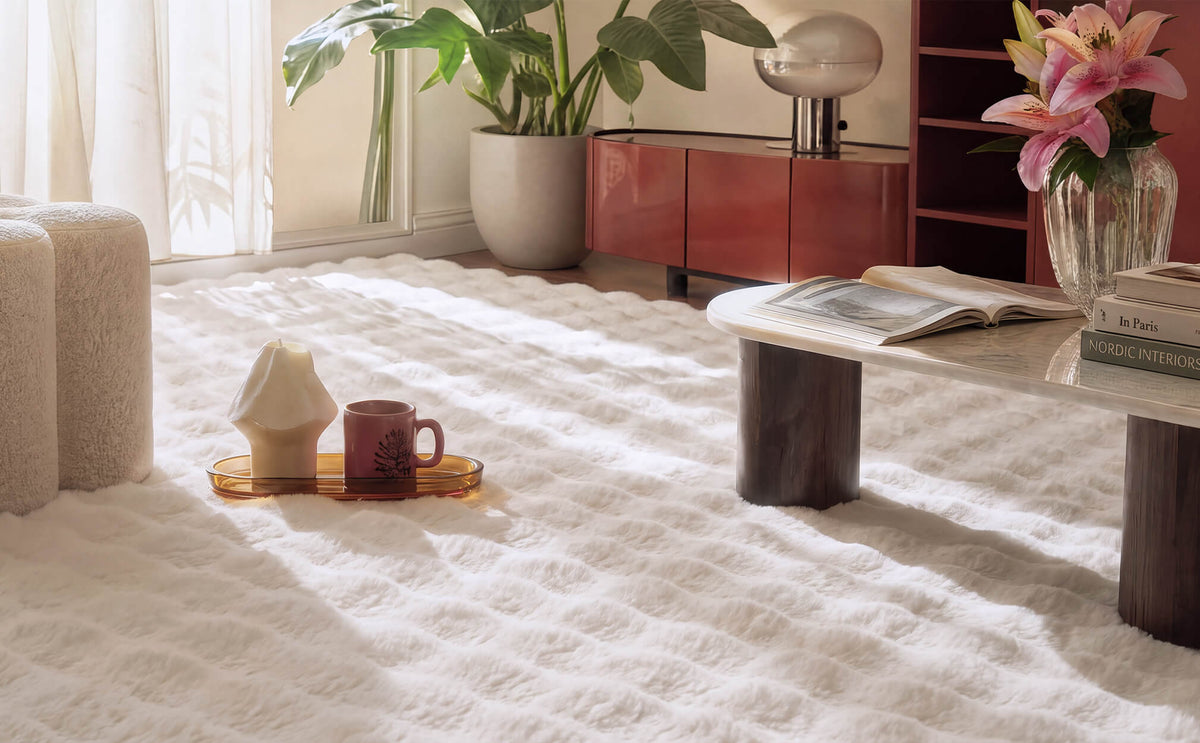 A cream Cloud Soft shag area rug creates a dreamy, cloud-like living space with its ultra-fluffy long-pile texture and plush checkered design, adding luxurious softness and cozy barefoot comfort beneath a modern coffee table surrounded by warm sunlight, elegant furniture, and fresh floral accents.