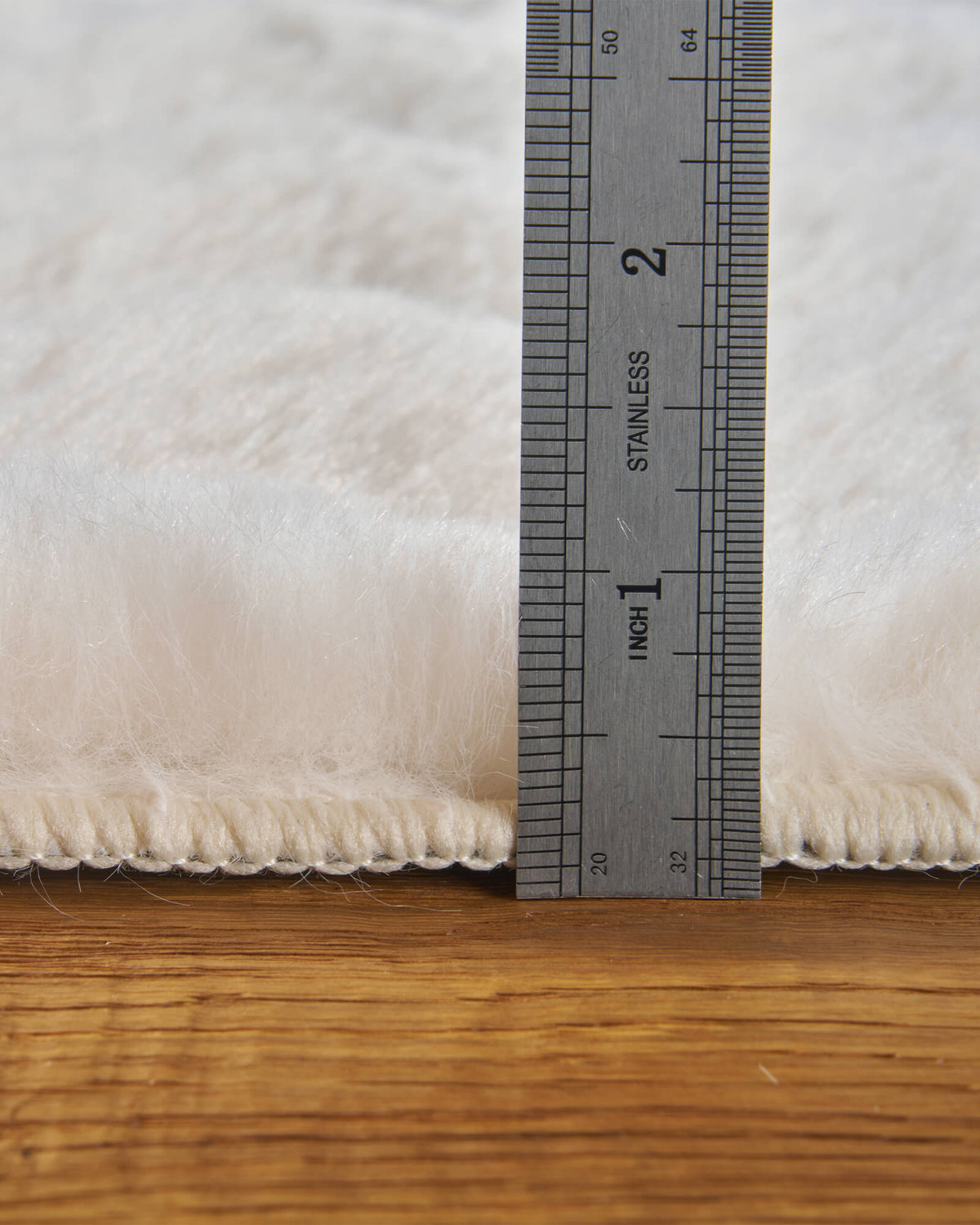 A close-up of a cream Cloud Soft shag area rug shows its ruler-measured pile height, exceptionally fluffy long-pile fibers, and thick, plush surface, highlighting its cloud-like softness and luxurious barefoot comfort for cozy bedrooms, living rooms, and relaxing home spaces.