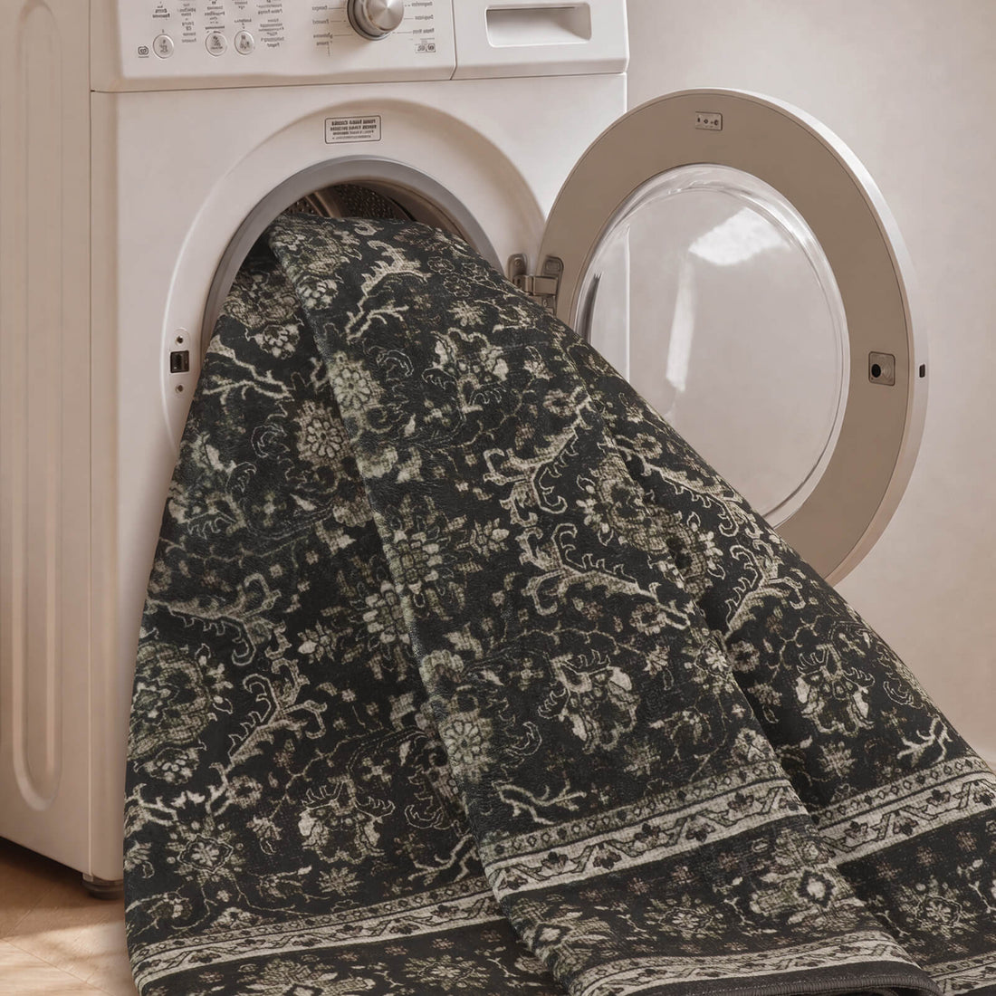 A dark charcoal vintage washable area rug is shown in a washing machine, highlighting its machine washable design, faded ornamental pattern, soft low-pile texture, and easy-care convenience for busy homes.