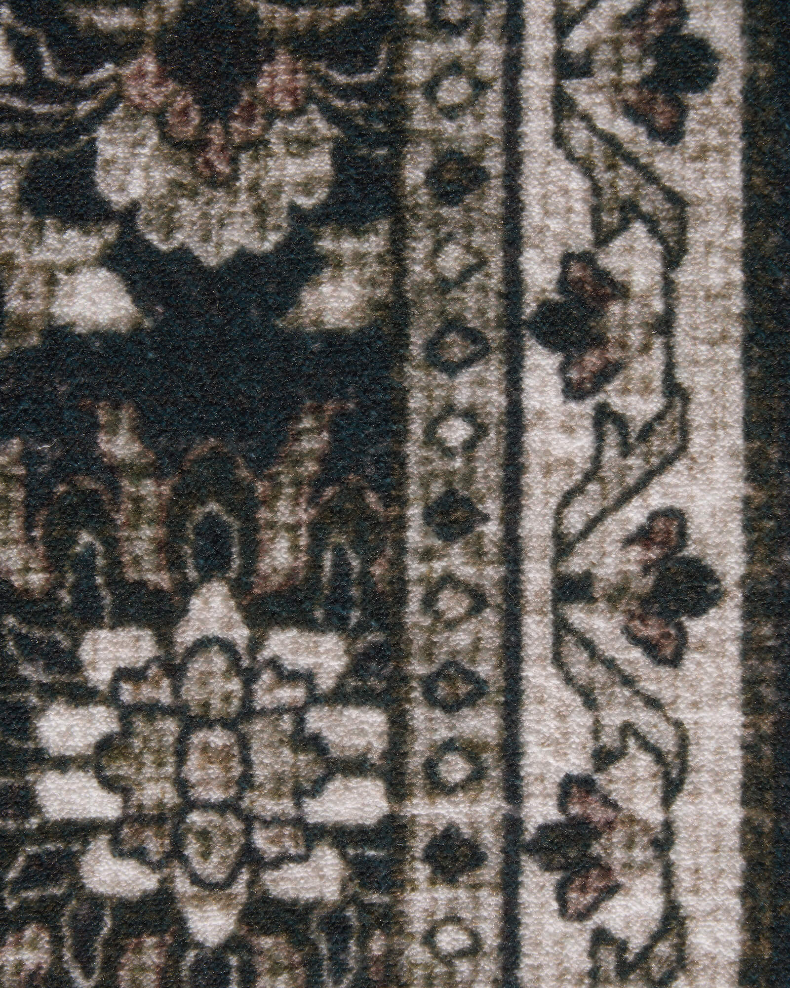 A close-up view of a dark charcoal vintage washable rug showing its distressed floral border, soft low-pile texture, and antique-inspired details for living rooms, bedrooms, and cozy home decor.
