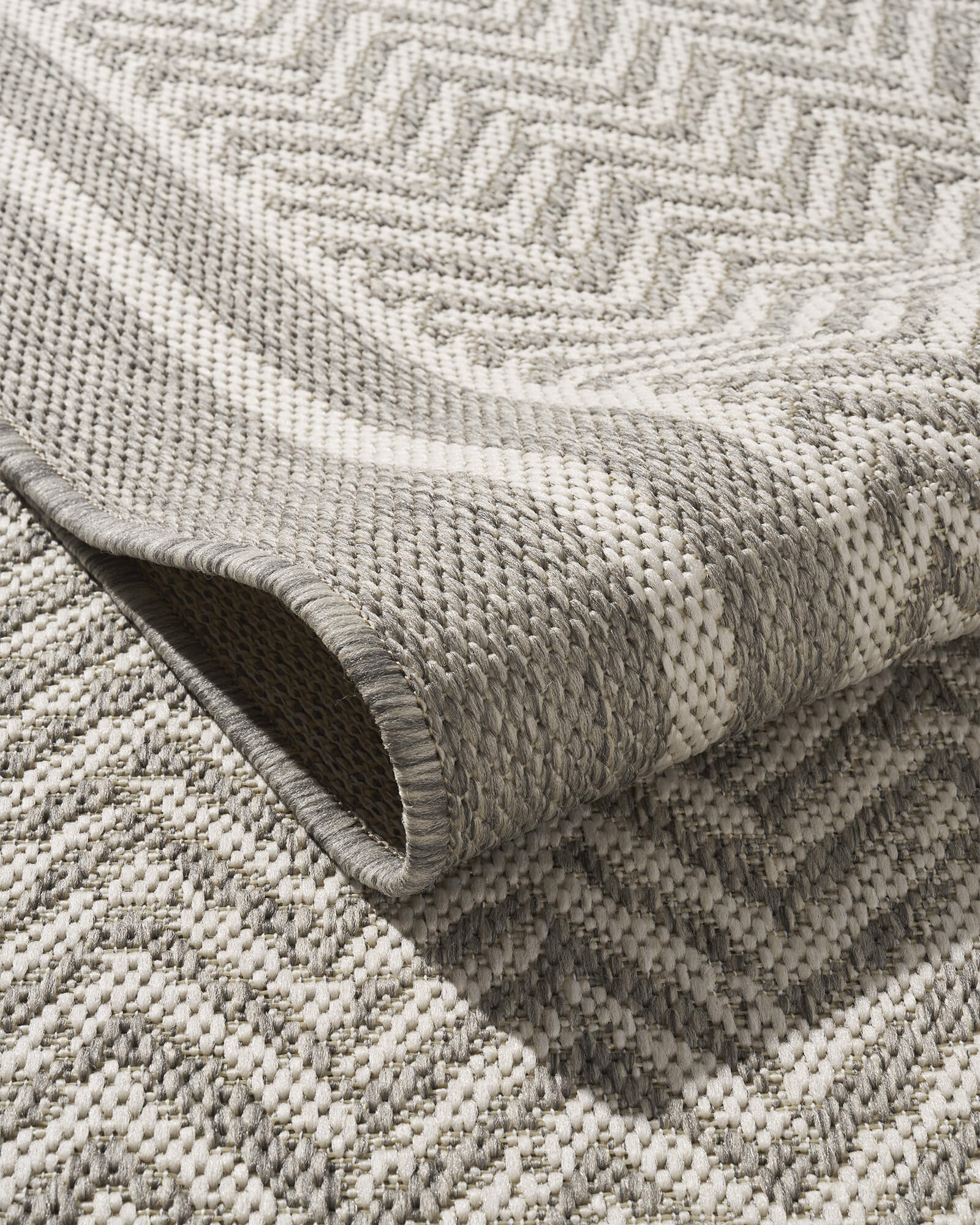 A foldable gray chevron indoor outdoor rug features a durable woven texture, raised geometric pattern, and reinforced edge for easy-care use on patios, porches, dining areas, and high-traffic spaces.