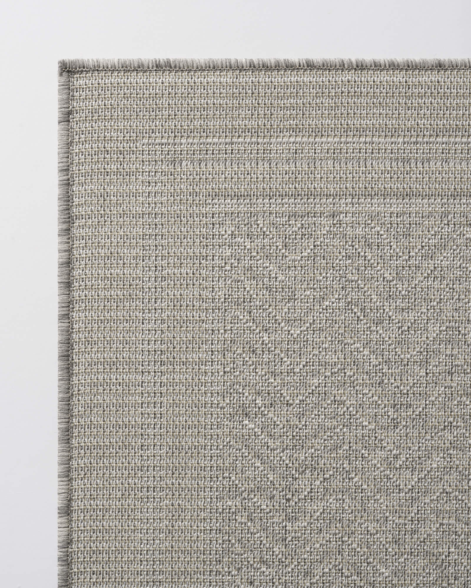 A close-up view of a gray chevron indoor outdoor rug shows its durable woven texture, reinforced border edge, and easy-care design for patios, porches, dining areas, and high-traffic spaces.