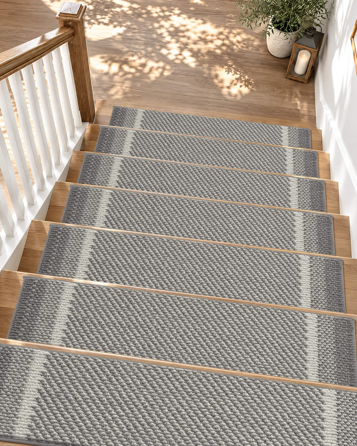 Gray gradient striped non-slip stair treads add modern style and everyday comfort to a sunlit wooden staircase, featuring a soft raised diagonal woven texture, contrasting white accent stripes, and neatly bound edges. Their anti-slip backing provides secure footing and helps protect hardwood steps, making them a practical choice for family-friendly homes with kids and pets.