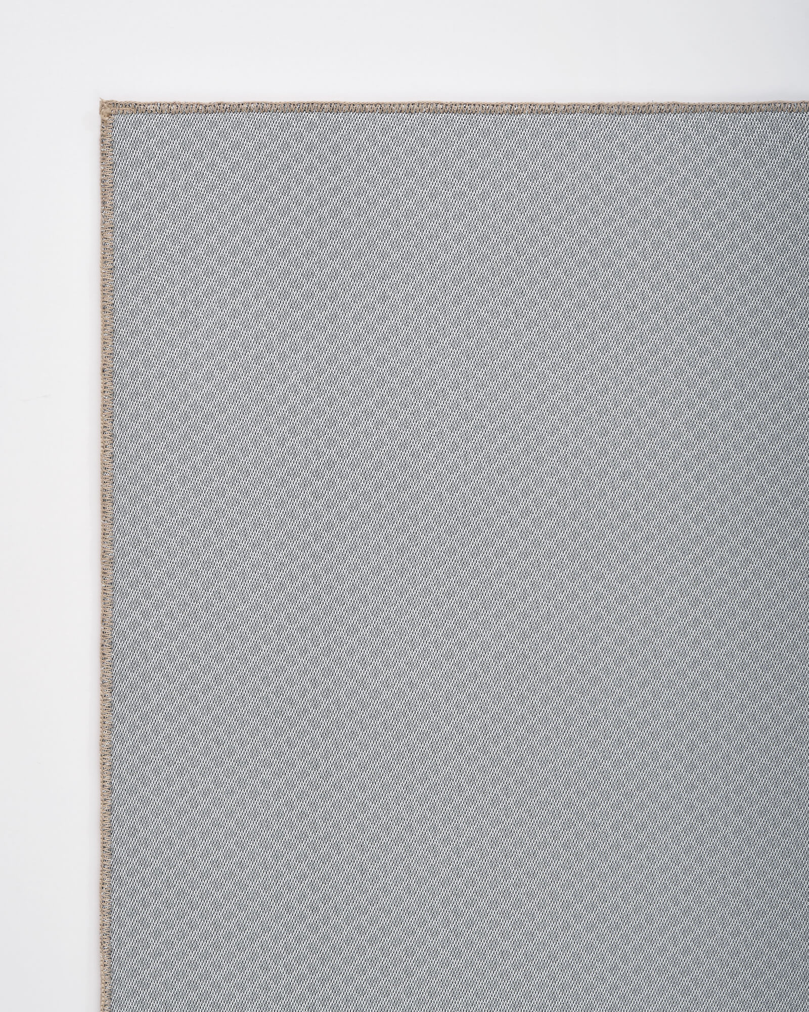 A close-up view of gray non-slip backing on a washable area rug shows its flexible construction and secure grip, designed for everyday use in living rooms, bedrooms, dining areas, and high-traffic spaces.