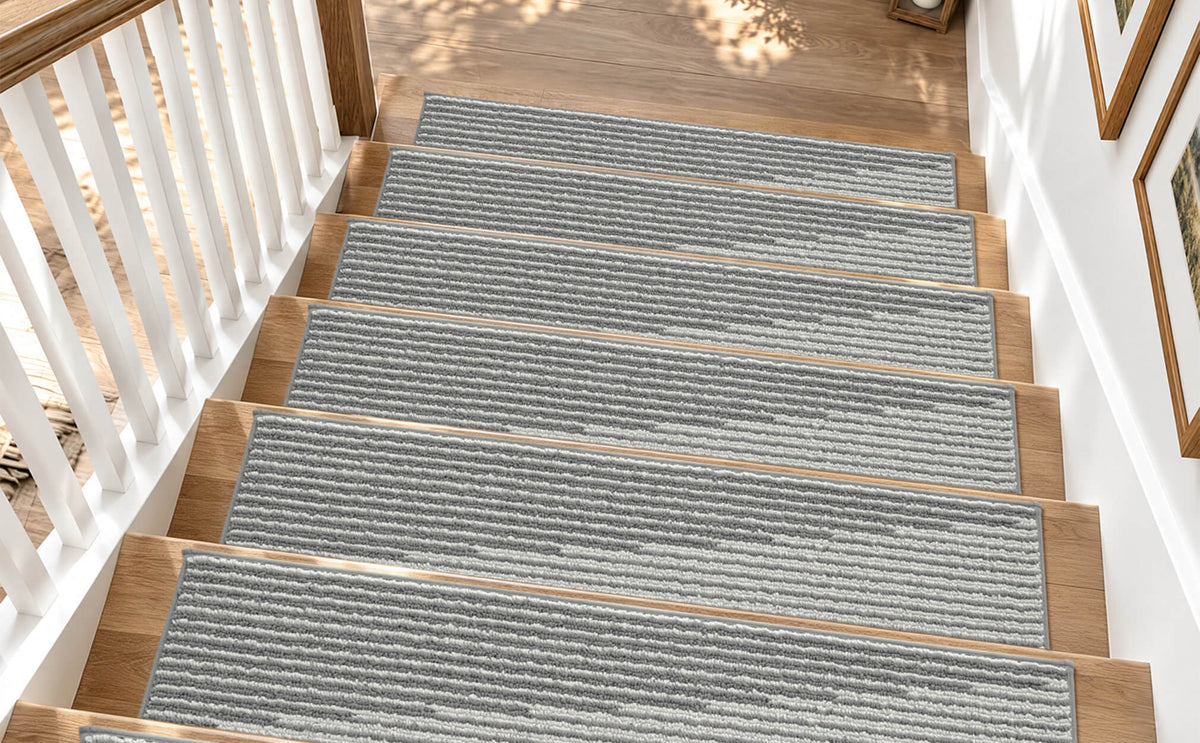 Gray and white striped non-slip stair treads neatly line a sunlit wooden staircase, featuring a soft ribbed woven texture, clean bound edges, and a modern linear pattern that provides comfortable footing, helps protect hardwood steps, and adds understated elegance to family-friendly home interiors.