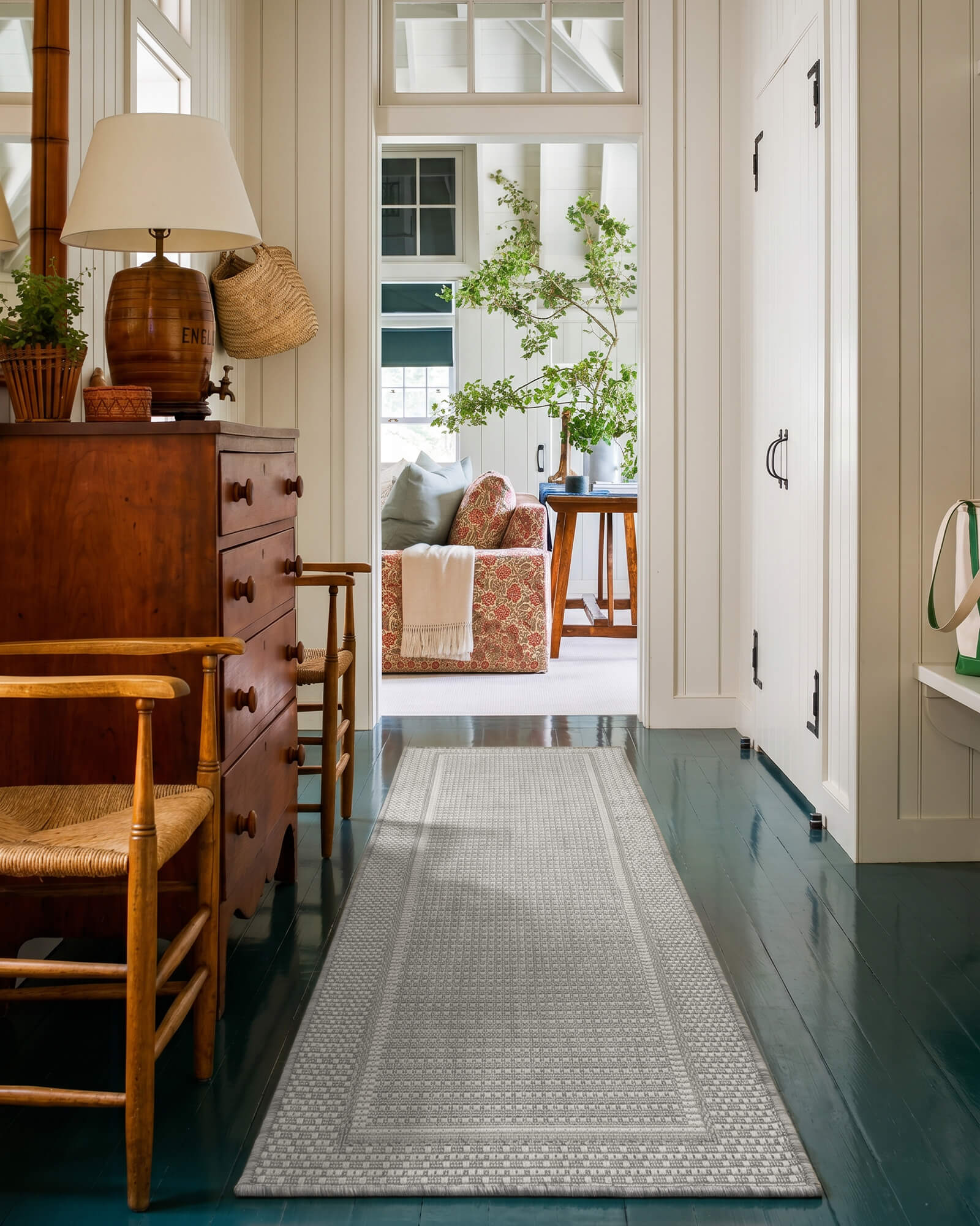 A gray woven indoor outdoor runner rug adds durable jute-look texture and easy-care style to a hallway or entryway with classic wood furniture, painted floors, and cozy home decor.