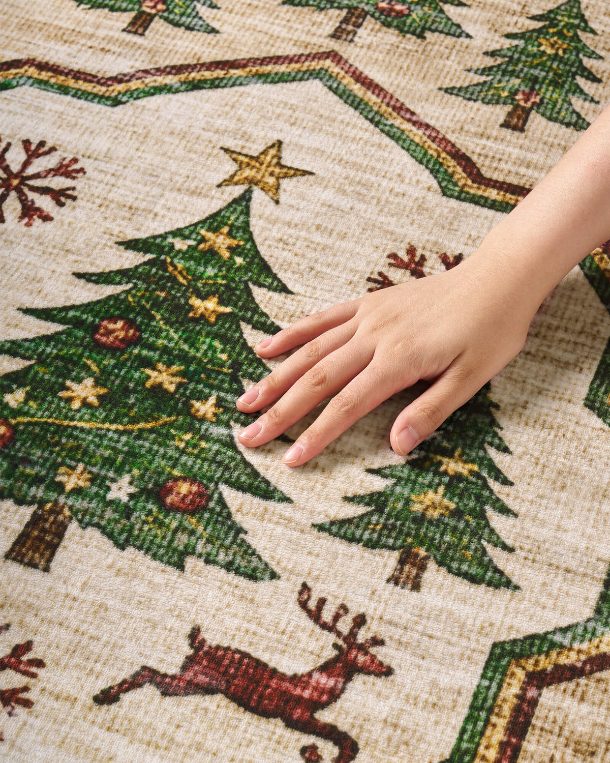 A close-up of a green Christmas vintage washable area rug shows a hand gently touching its soft, comfortable surface, highlighting festive Christmas tree motifs, golden stars, delicate snowflakes, and playful reindeer illustrations. Its vintage-inspired texture brings cozy warmth and nostalgic holiday charm to Christmas living rooms and family spaces.