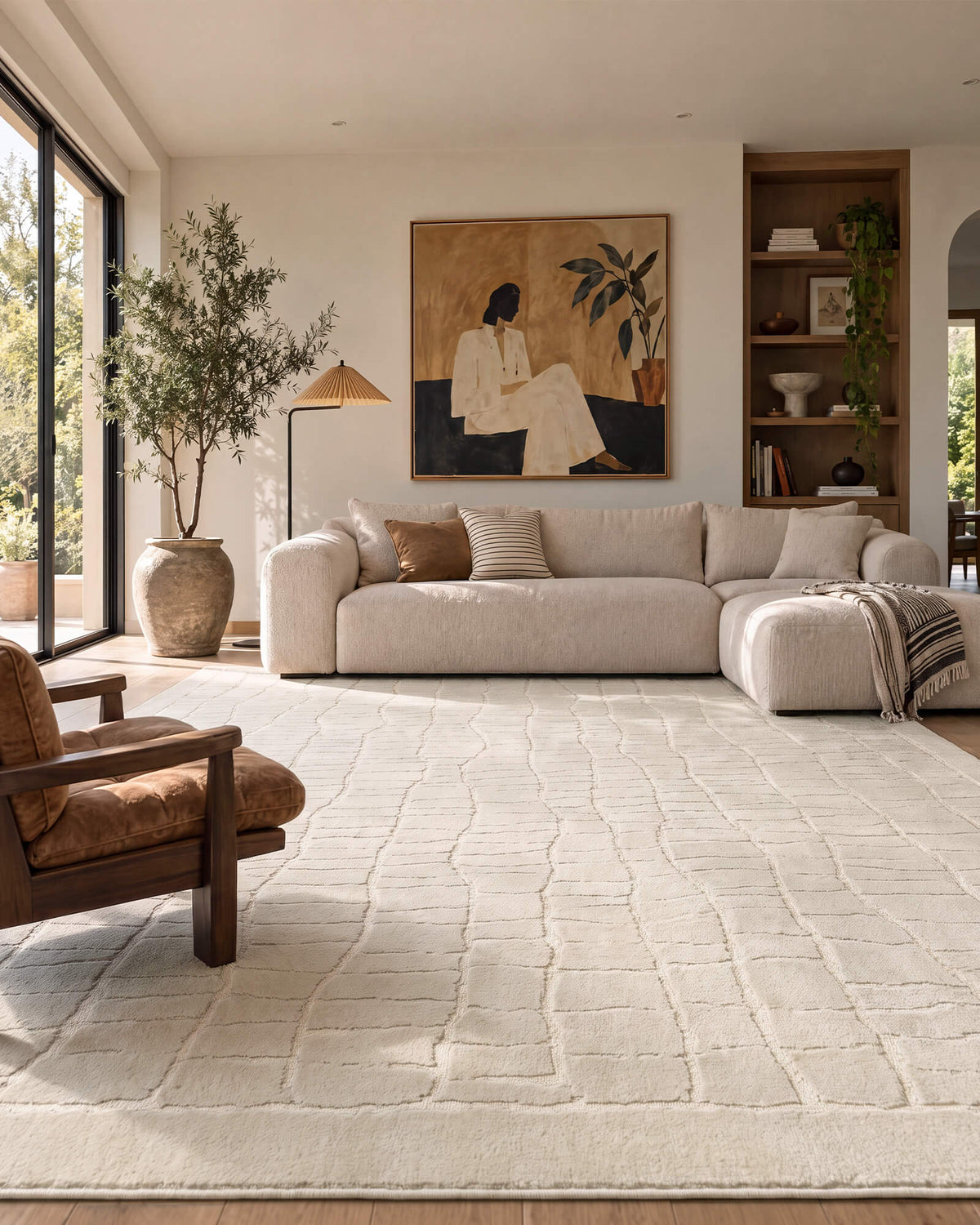 An ivory luxury Wilton jacquard area rug with a raised grid texture adds sculptural softness and refined dimension to a modern living room with a cream sectional sofa, curated artwork, warm wood accents, and natural light.