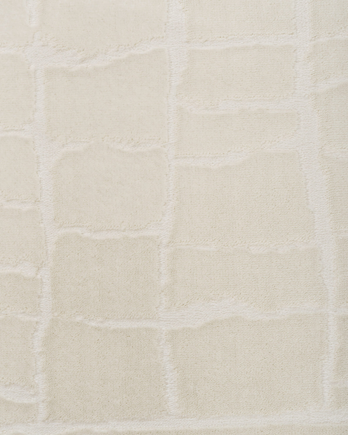 A close-up view of an ivory luxury Wilton jacquard rug highlights its abstract block texture, plush dimensional surface, and refined tonal softness for elevated living room and bedroom decor.