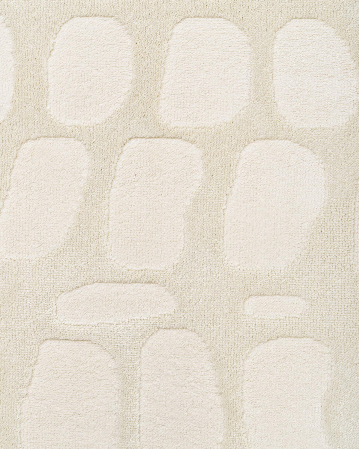 A macro close-up of an ivory premium Wilton jacquard rug highlights its raised pebble-inspired pattern, plush dimensional texture, and refined tonal softness for luxury living room and bedroom decor.