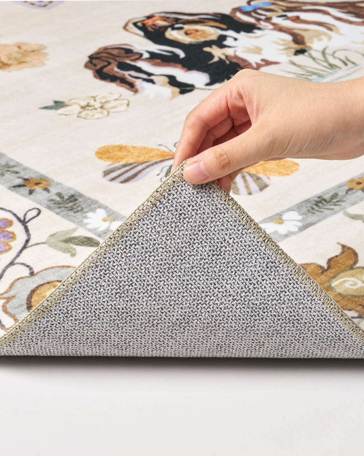 A close-up view of an ivory soft kids rug showing its folded corner, gray non-slip backing, cute animal border pattern, and neatly finished edge for safe, cozy nursery, playroom, and children’s bedroom use.