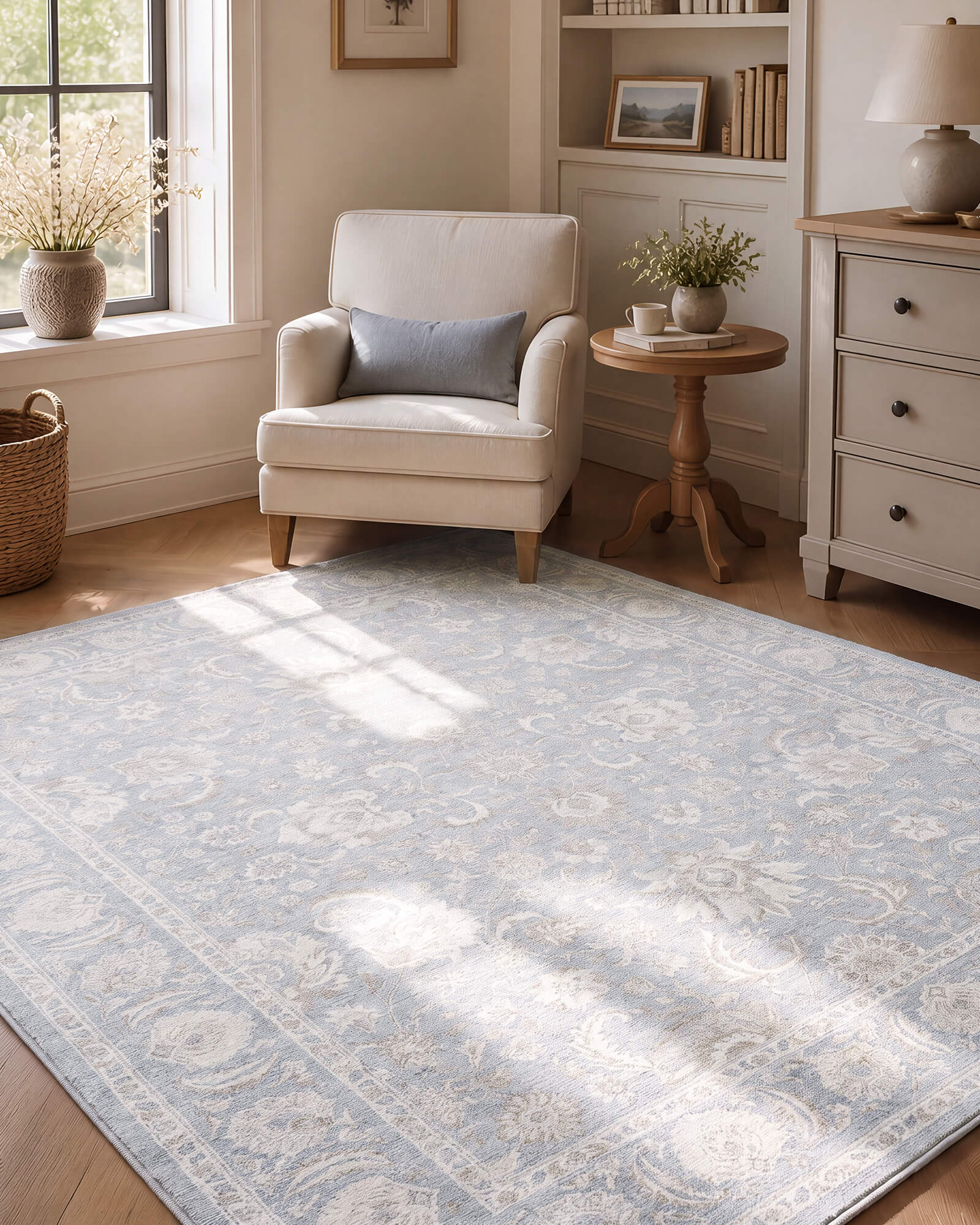 A light blue vintage washable area rug with a faded ornamental pattern adds soft color and timeless charm to a cozy reading corner with an accent chair, side table, built-in shelves, and warm natural light.