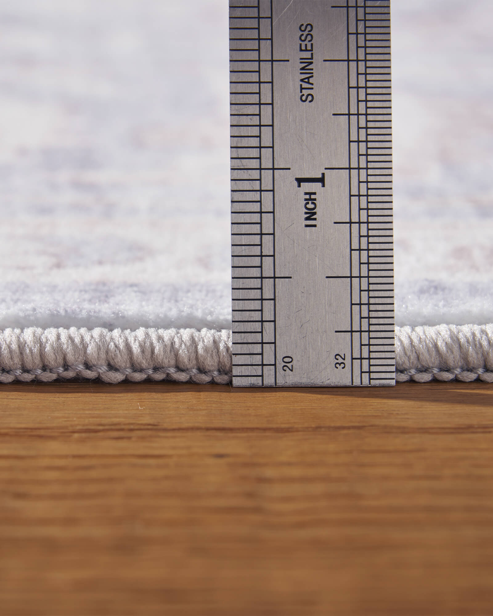 A close-up view of a light blue vintage washable rug showing its ruler-measured pile height, soft low-profile surface, and finished edge for easy placement in living rooms, bedrooms, and family spaces.