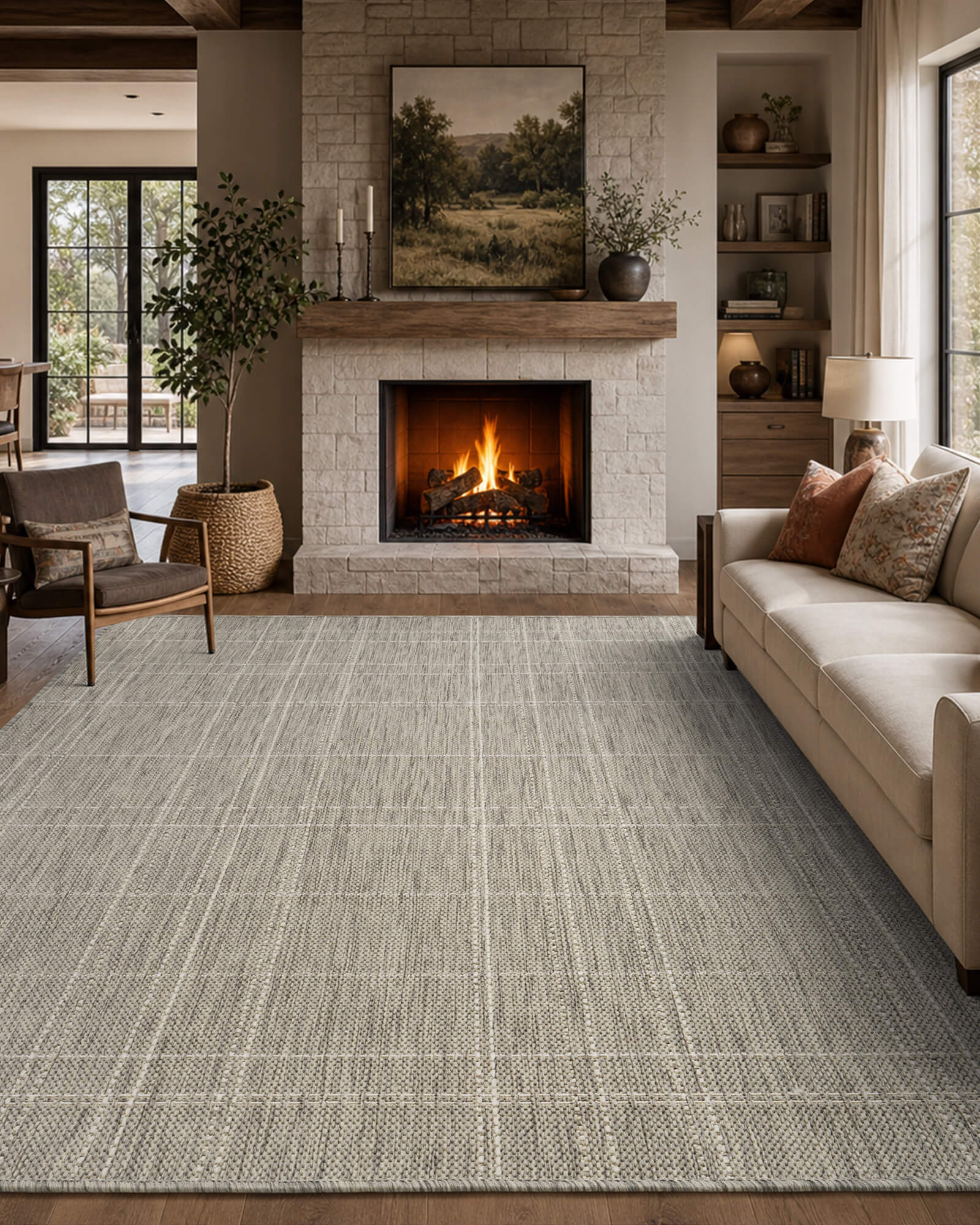 A light gray grid indoor outdoor rug adds clean woven texture to a cozy fireplace lounge with a cream sofa, stone mantel, built-in shelves, warm lighting, and relaxed farmhouse decor.