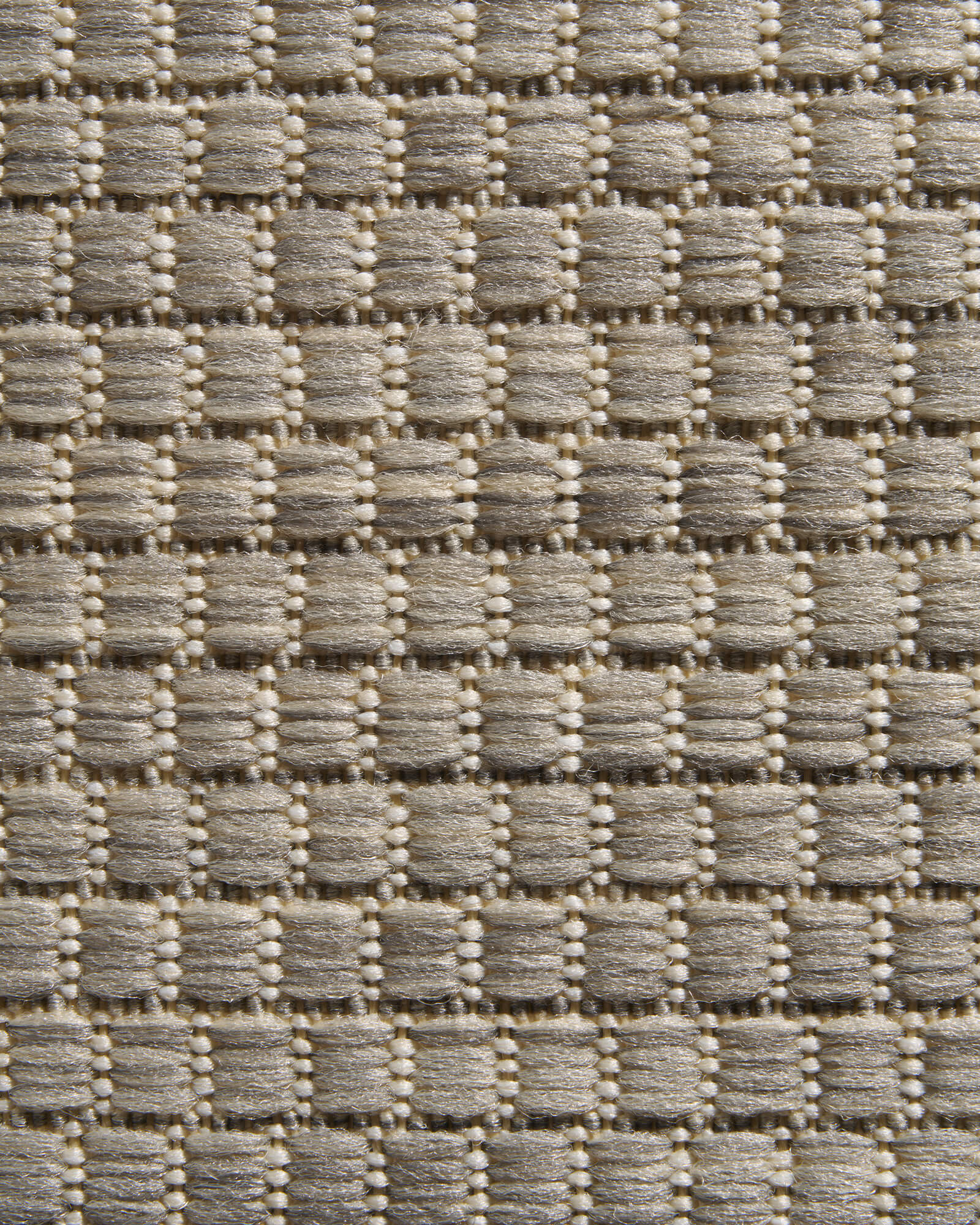 A close-up view of a light gray plain weave outdoor rug highlights its raised basketweave texture, durable woven surface, and clean natural style for patios, decks, porches, and outdoor entryways.
