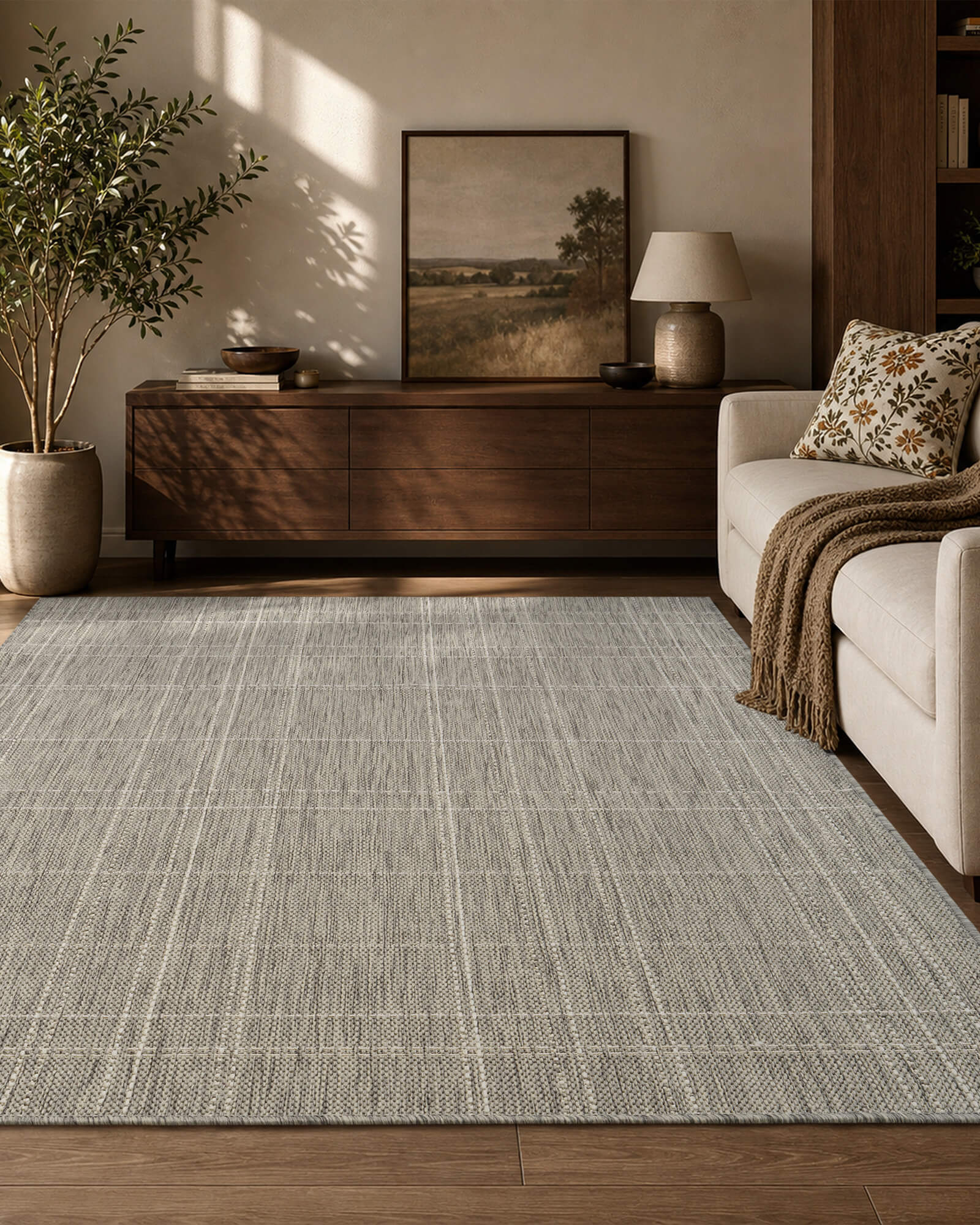A light gray subtle grid indoor outdoor area rug adds clean woven texture to a cozy living room with a wood console table, cream sofa, soft sunlight, and warm natural decor.