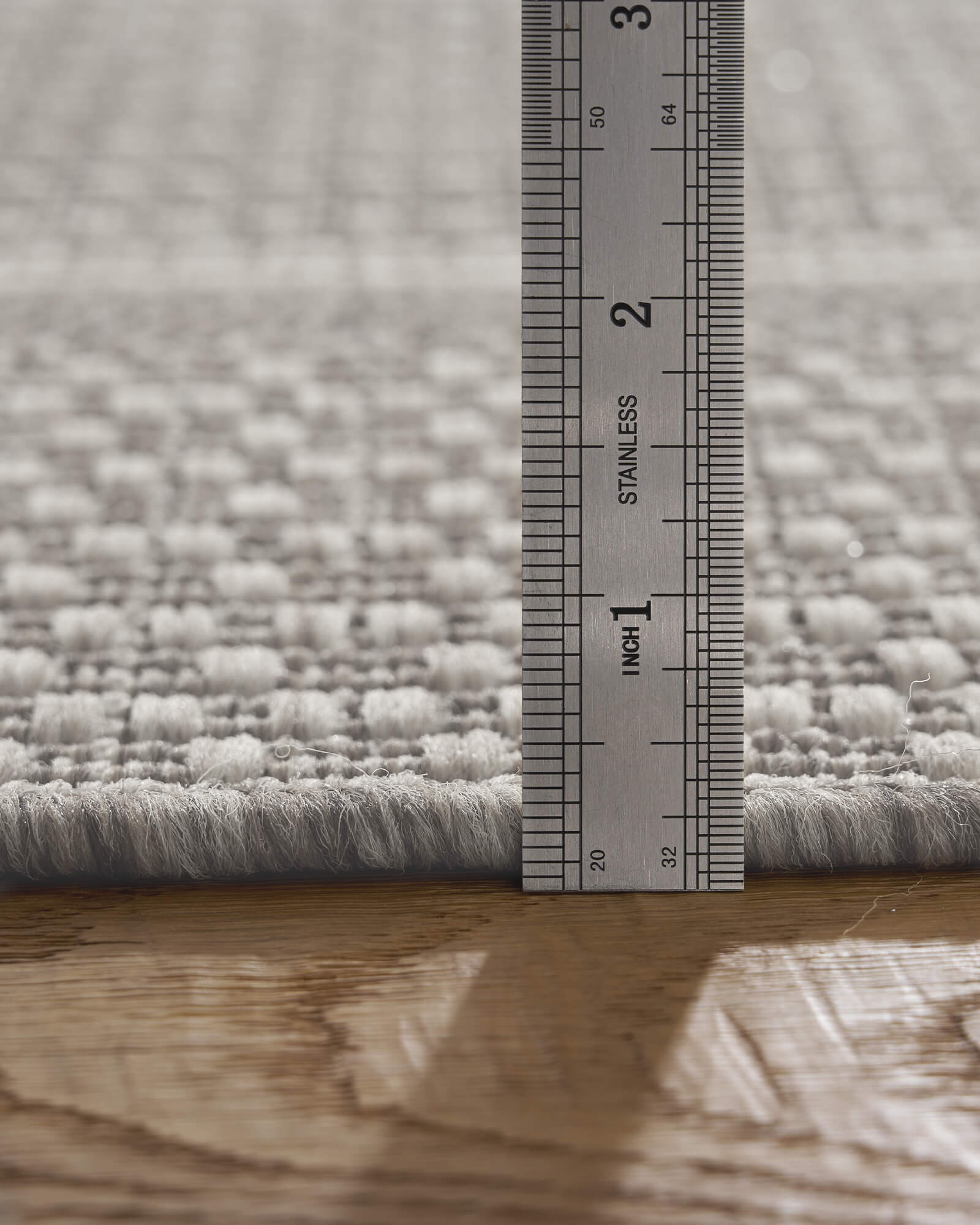 A low-profile gray woven indoor outdoor rug features a durable jute-look texture and slim pile height, making it easy to place under furniture and ideal for patios, kitchens, entryways, and high-traffic spaces.