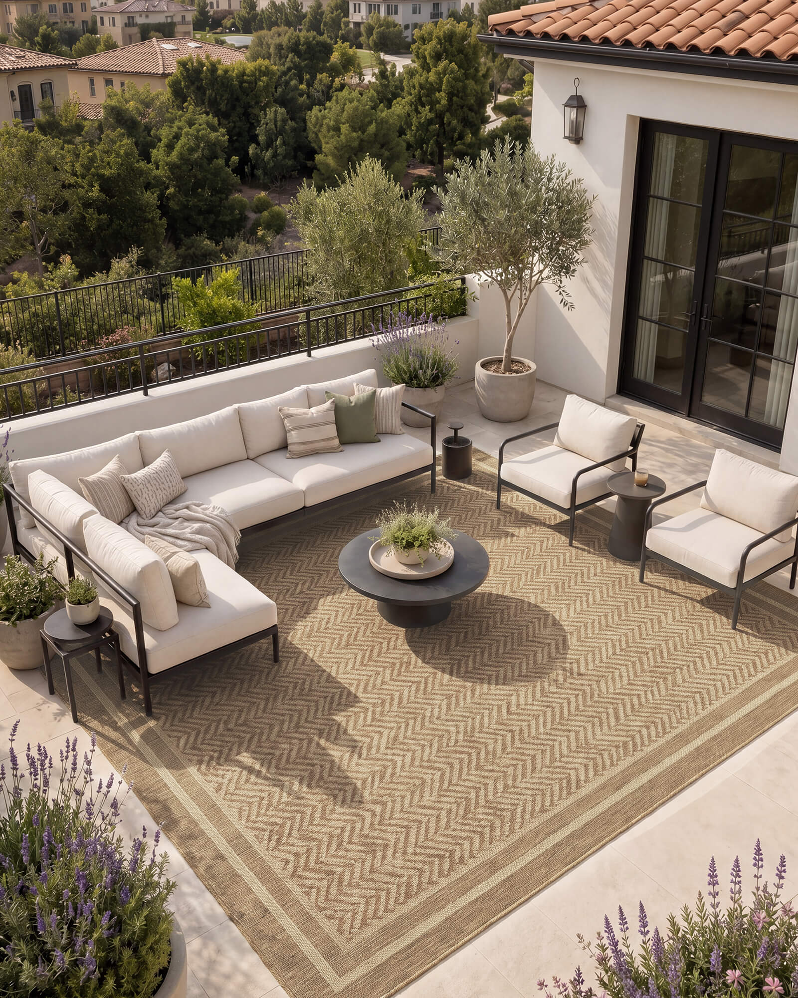 A natural chevron indoor outdoor rug adds durable woven texture and easy-care style to a balcony patio lounge with modern outdoor seating, potted greenery, and warm open-air decor.