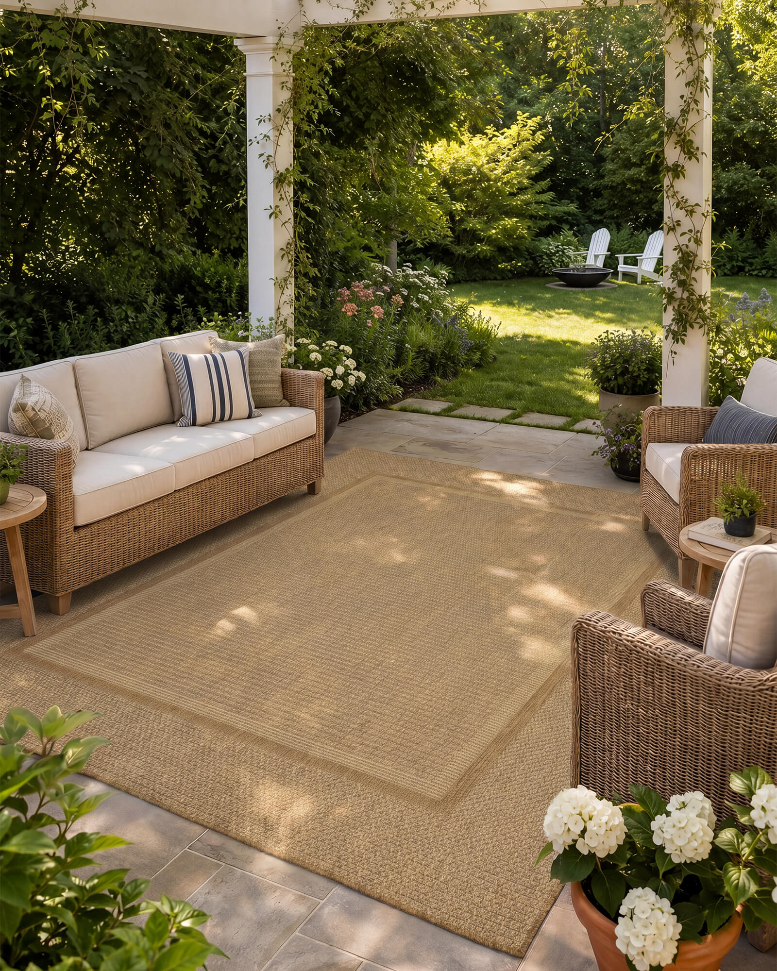 A natural woven indoor outdoor rug adds durable, easy-care texture to a cozy patio seating area with wicker furniture, garden greenery, and outdoor lounge style.