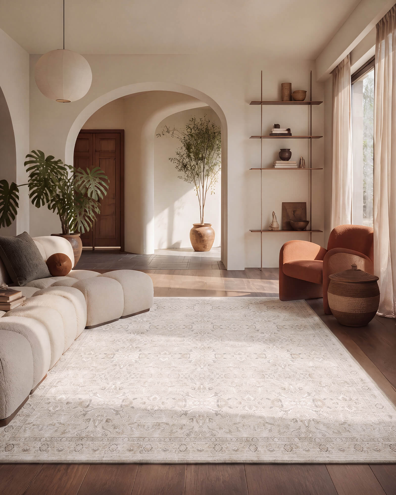 A neutral vintage washable area rug with a soft distressed pattern brings calm texture to a minimal living room with an arched doorway, modular sofa, warm sunlight, and earthy modern decor.