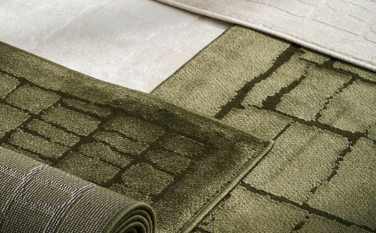 A close-up comparison of olive green and ivory luxury Wilton jacquard rugs highlights their raised grid patterns, plush dimensional texture, structured woven backing, and refined premium finish for elevated home decor.