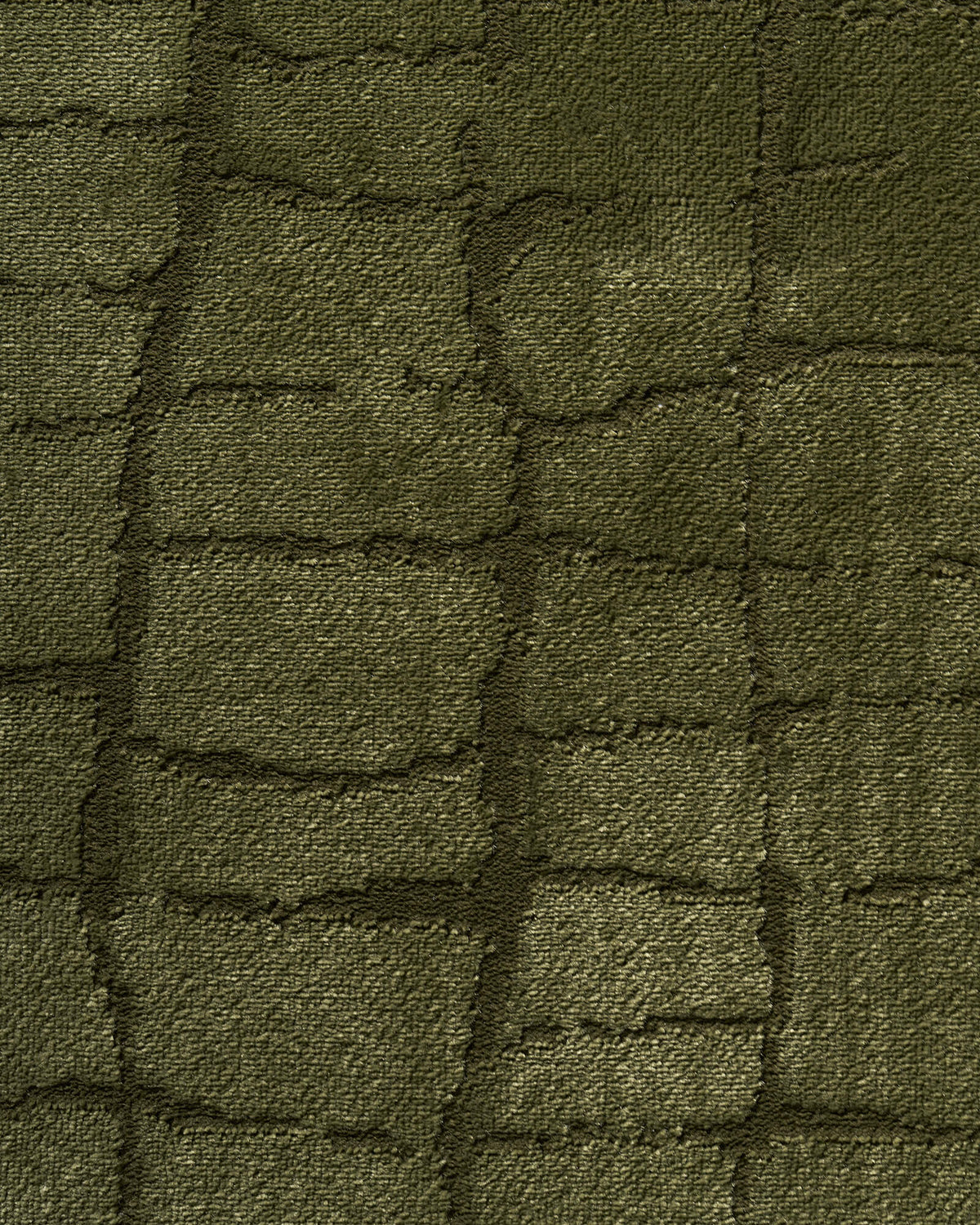 A macro close-up of an olive green luxury Wilton jacquard rug highlights its raised grid texture, dimensional woven surface, and rich tonal depth for refined living room and bedroom styling.