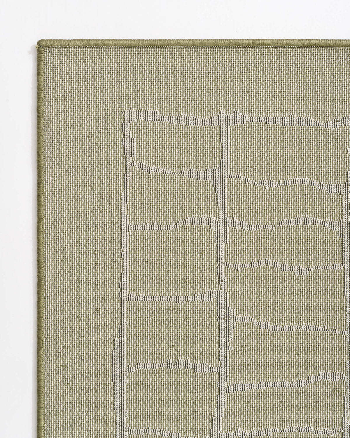 A close-up reverse corner view of an olive green luxury Wilton jacquard rug highlights its structured woven backing, tonal raised grid pattern, and refined bound edge for elevated living room and bedroom styling.