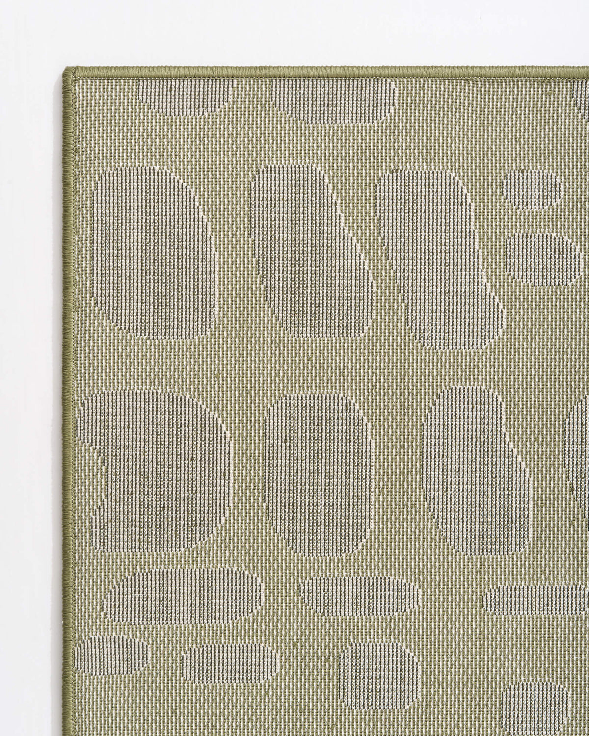 A close-up corner back view of an olive green premium Wilton jacquard rug highlights its tonal pebble-inspired pattern, structured woven backing, and refined bound edge for elevated living room and bedroom styling.
