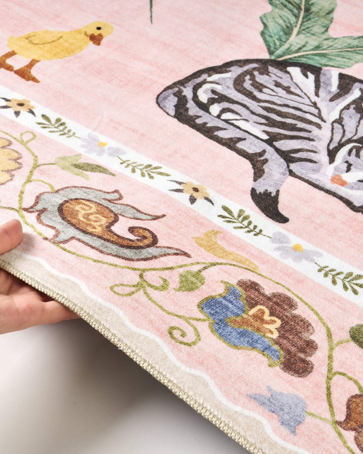 A close-up view of a pink soft kids rug highlights its cute zebra, duck, and floral border details, along with a gentle bound edge and comfortable surface for nurseries, playrooms, and children’s bedrooms.