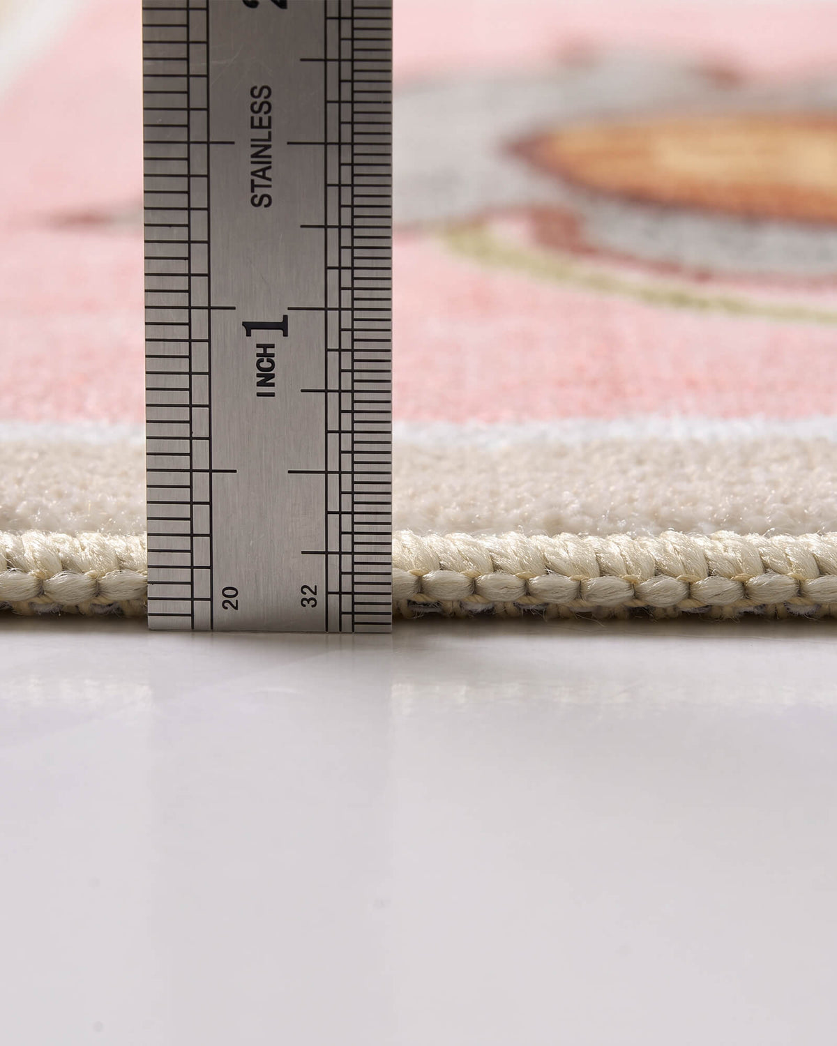 A close-up view of a pink soft kids rug showing its ruler-measured pile height, plush comfortable surface, and neatly bound edge for safe and cozy playroom, nursery, and children’s bedroom use.