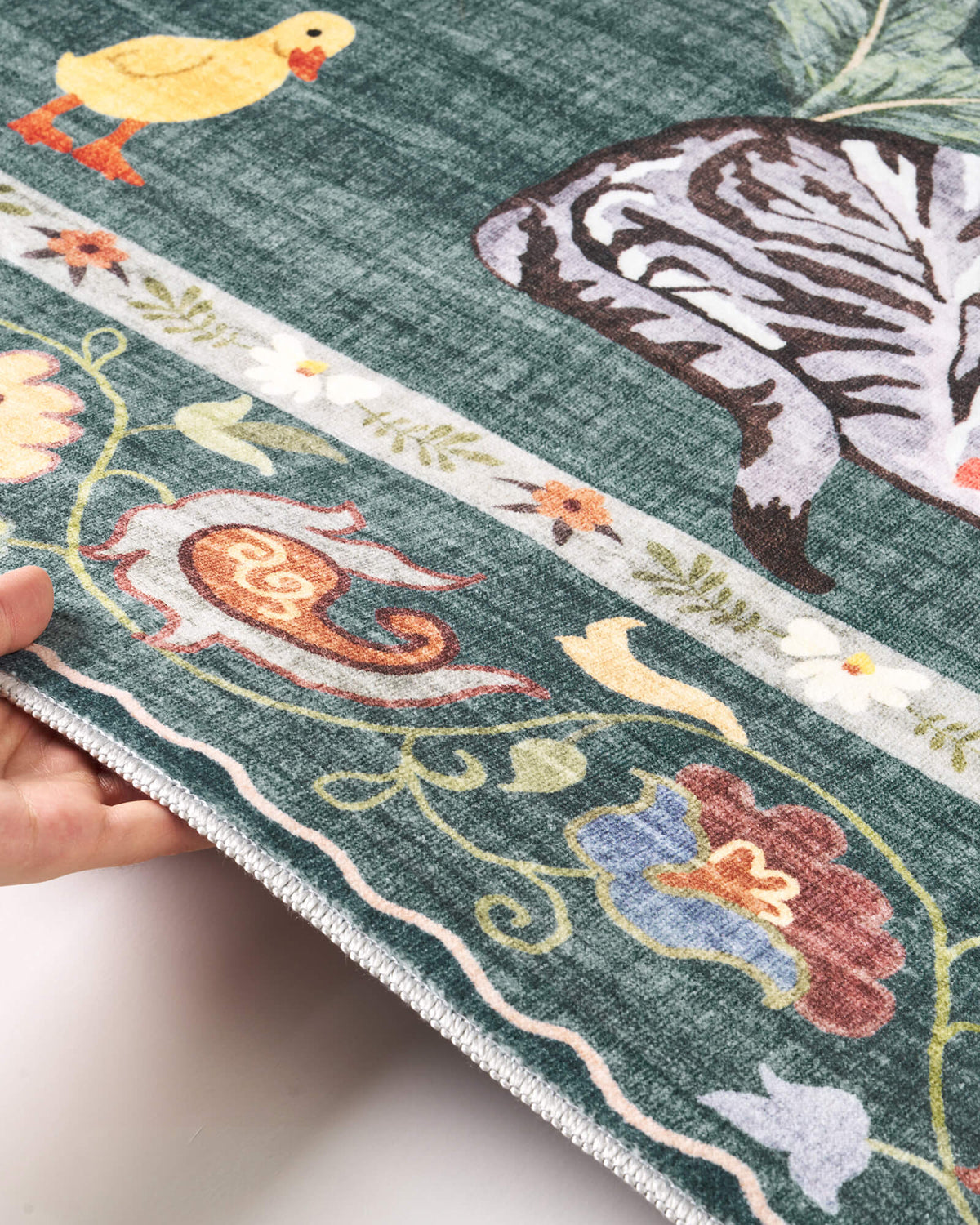 A close-up view of a teal soft kids rug highlights its cute zebra, duck, and floral border details, along with a gentle bound edge and comfortable surface for nurseries, playrooms, and children’s bedrooms.