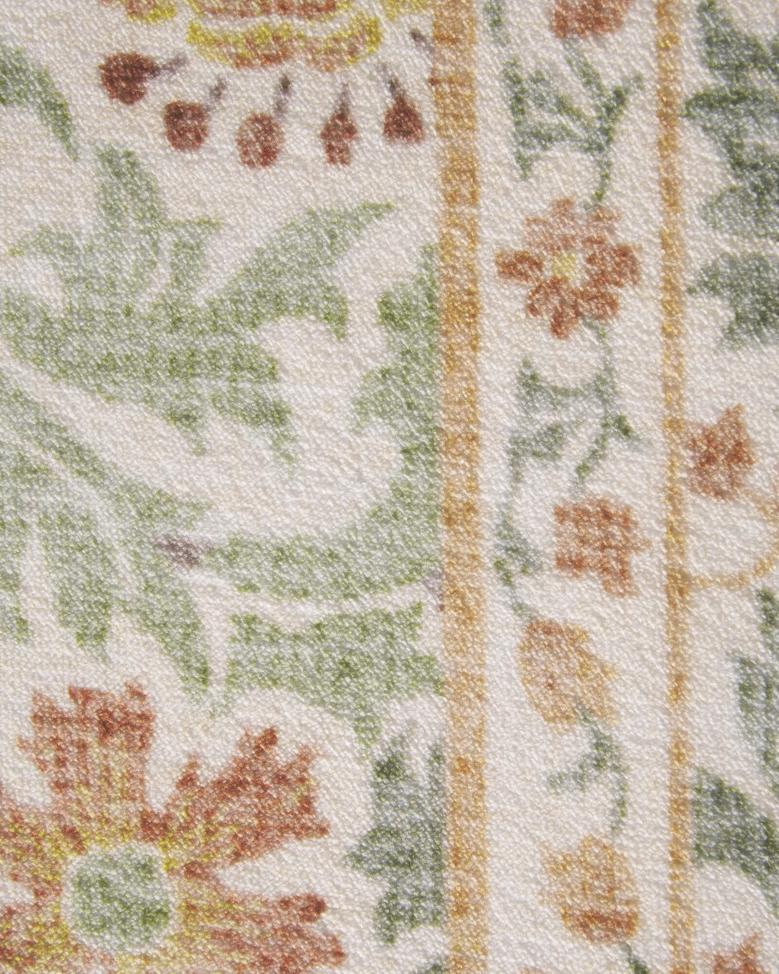 A close-up view of a vintage floral area rug showcasing soft botanical motifs, delicate flower details, and a textured surface with a timeless traditional design.