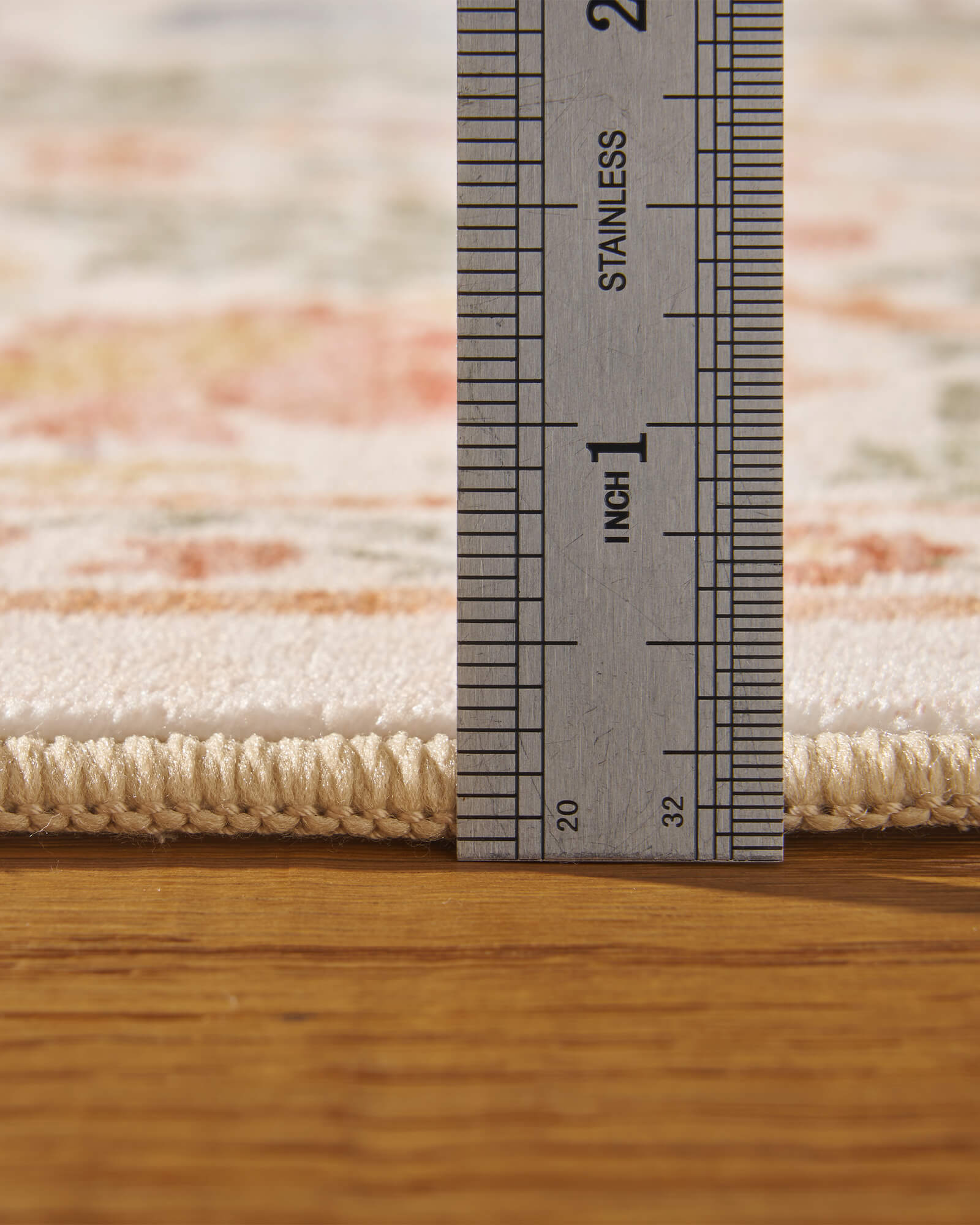 A close-up view of a washable floral area rug showing its soft low-pile texture, plush surface, and durable construction with measured thickness for everyday home use.