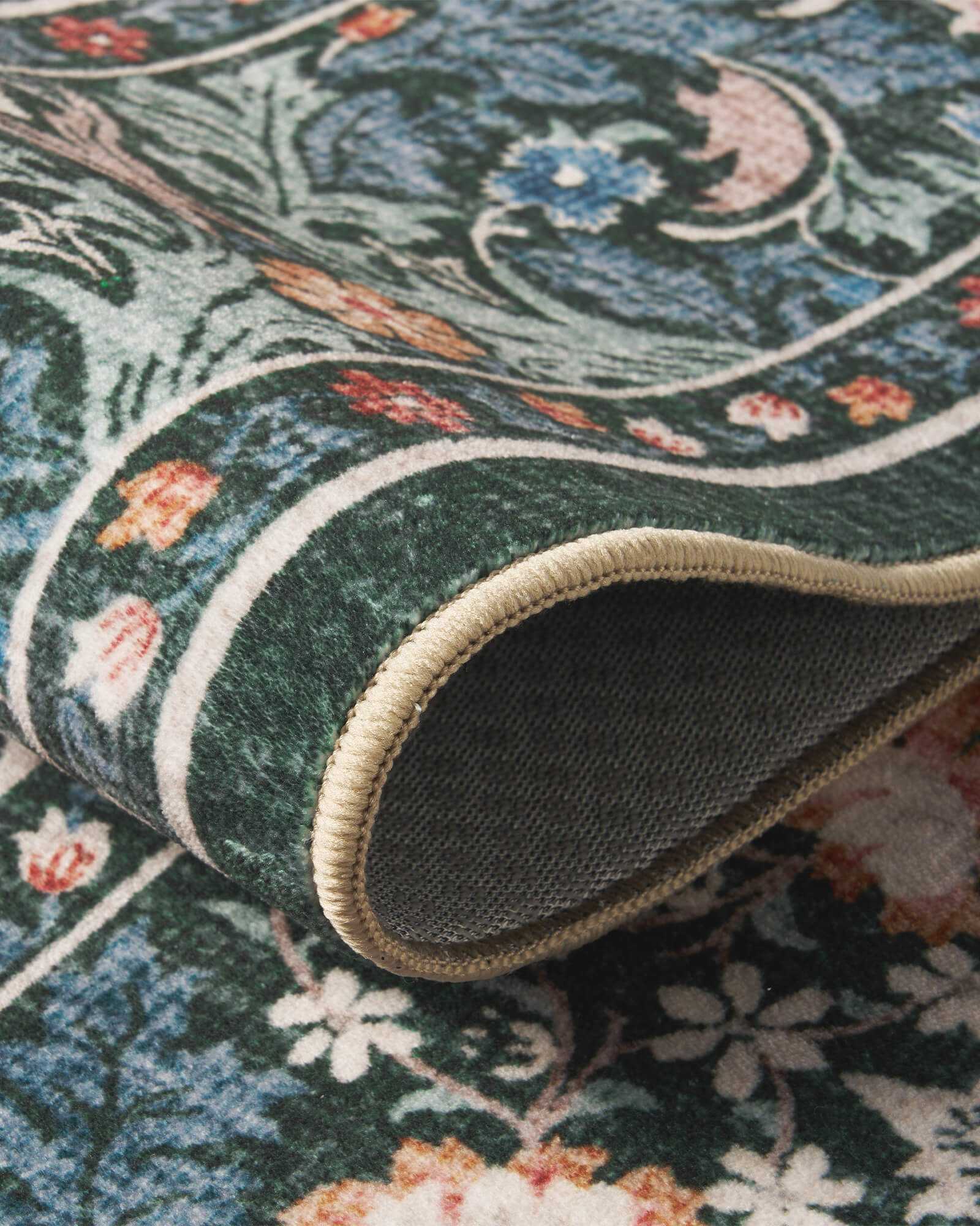 A close-up view of a washable vintage floral area rug featuring a dark green botanical pattern, soft low-pile texture, detailed floral motifs, finished edges, and a durable non-slip backing for everyday comfort.